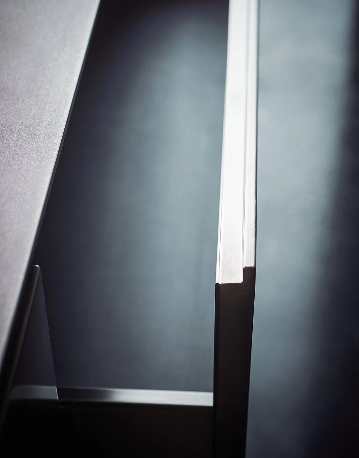Nahaufnahme eines Metallgegenstands, wahrscheinlich ein Fensterrahmen oder eine Tür aus Edelstahl, mit Fokus auf eine schmale, vertikale Kante im Profil.