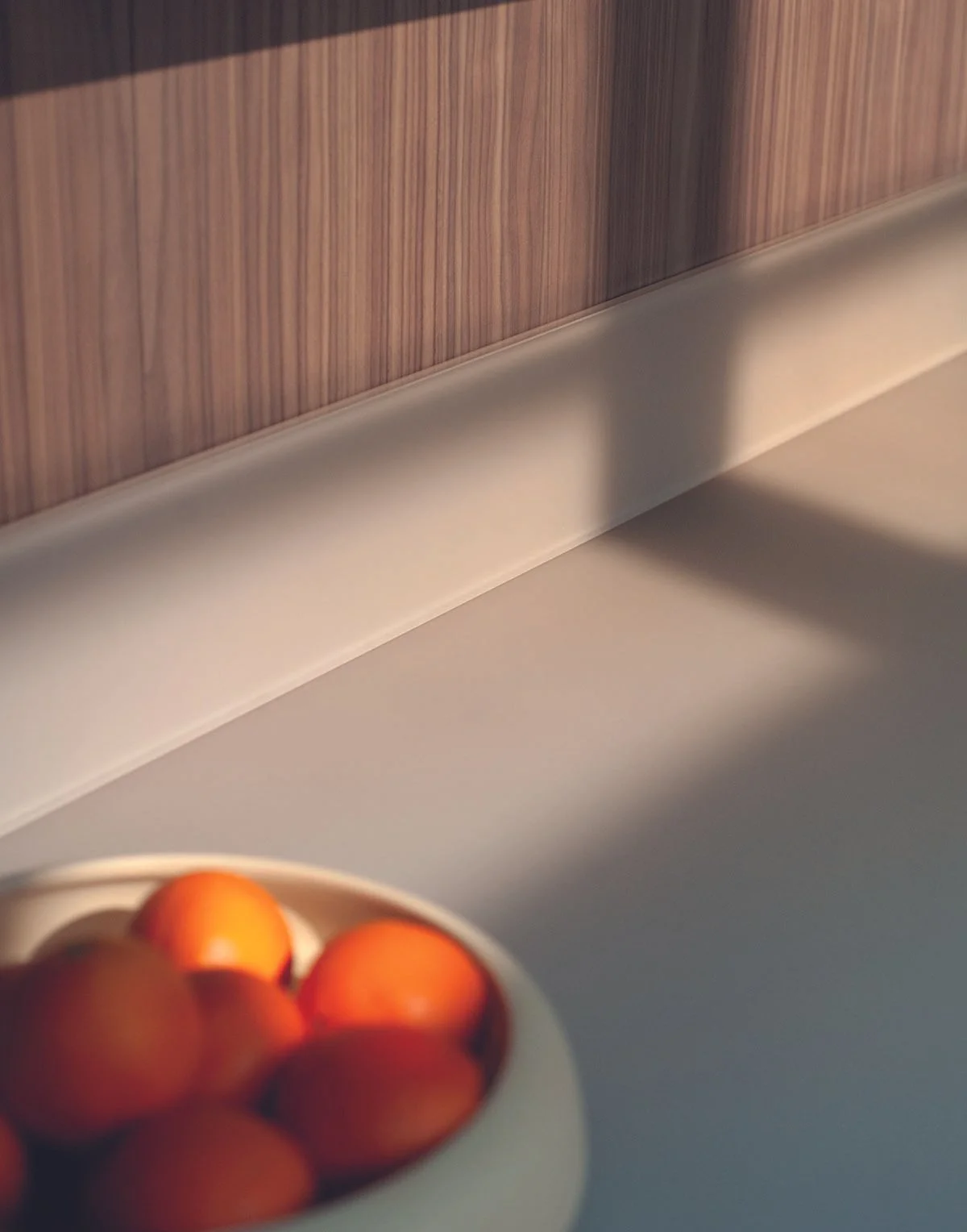 Eine weiße Schüssel mit Orangen auf einer weißen Oberfläche vor einer Holzvertäfelung.