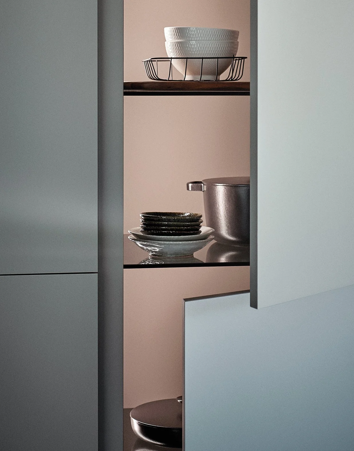 Ein Blick in eine moderne, minimalistische Küchenschranköffnung mit weißen und schwarzen Geschirrteilen und Kochtöpfen.