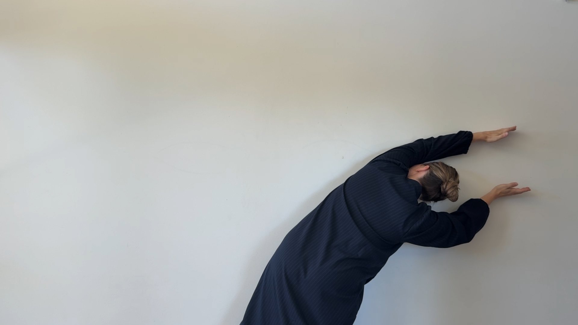 Marnie Tomczyk pressing her body against a white wall in the performance video 'Try to Bend a Wall'