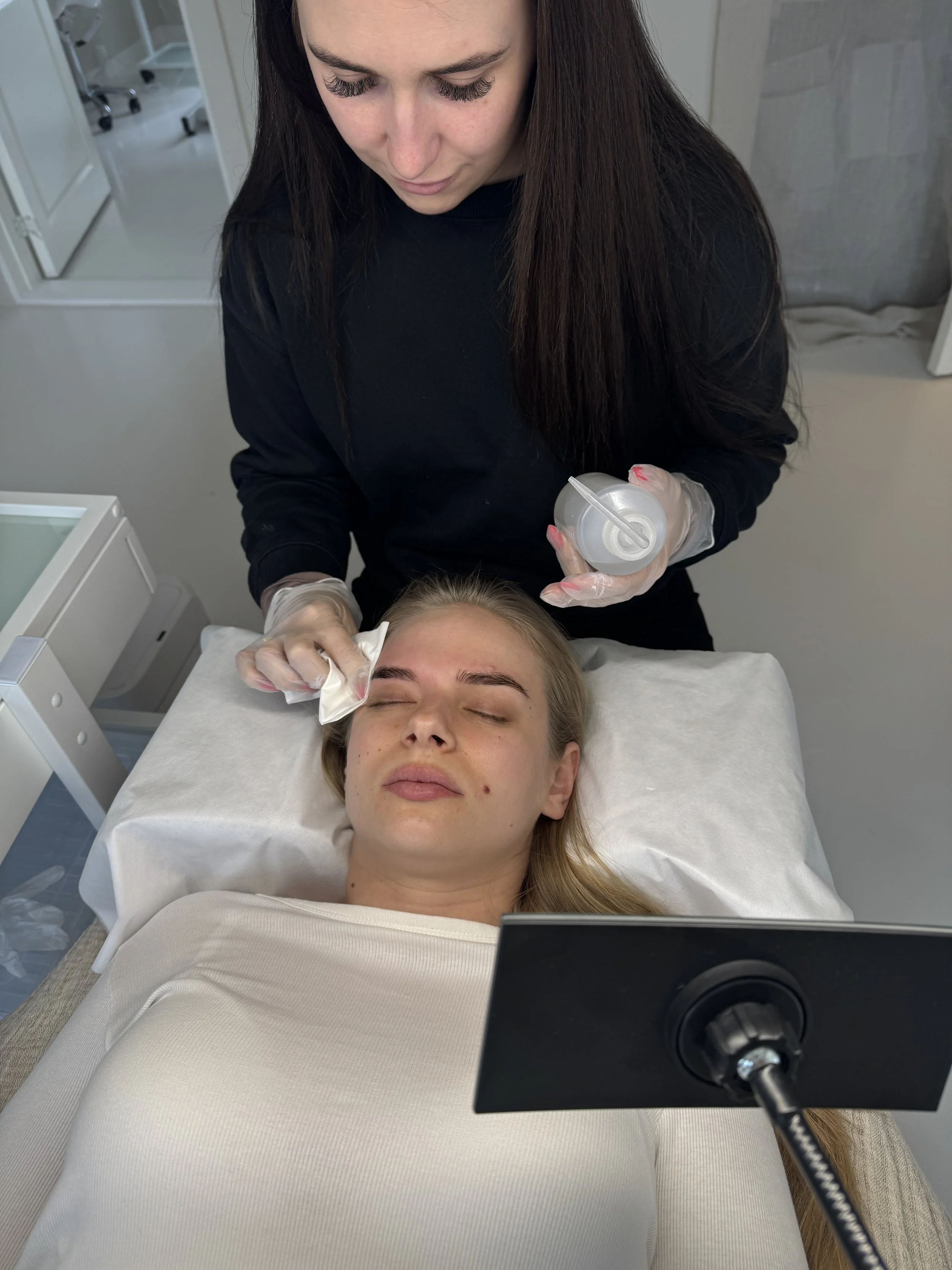 En kvindelig person fås injektion i ansigtet af en professionel i en klinik.
