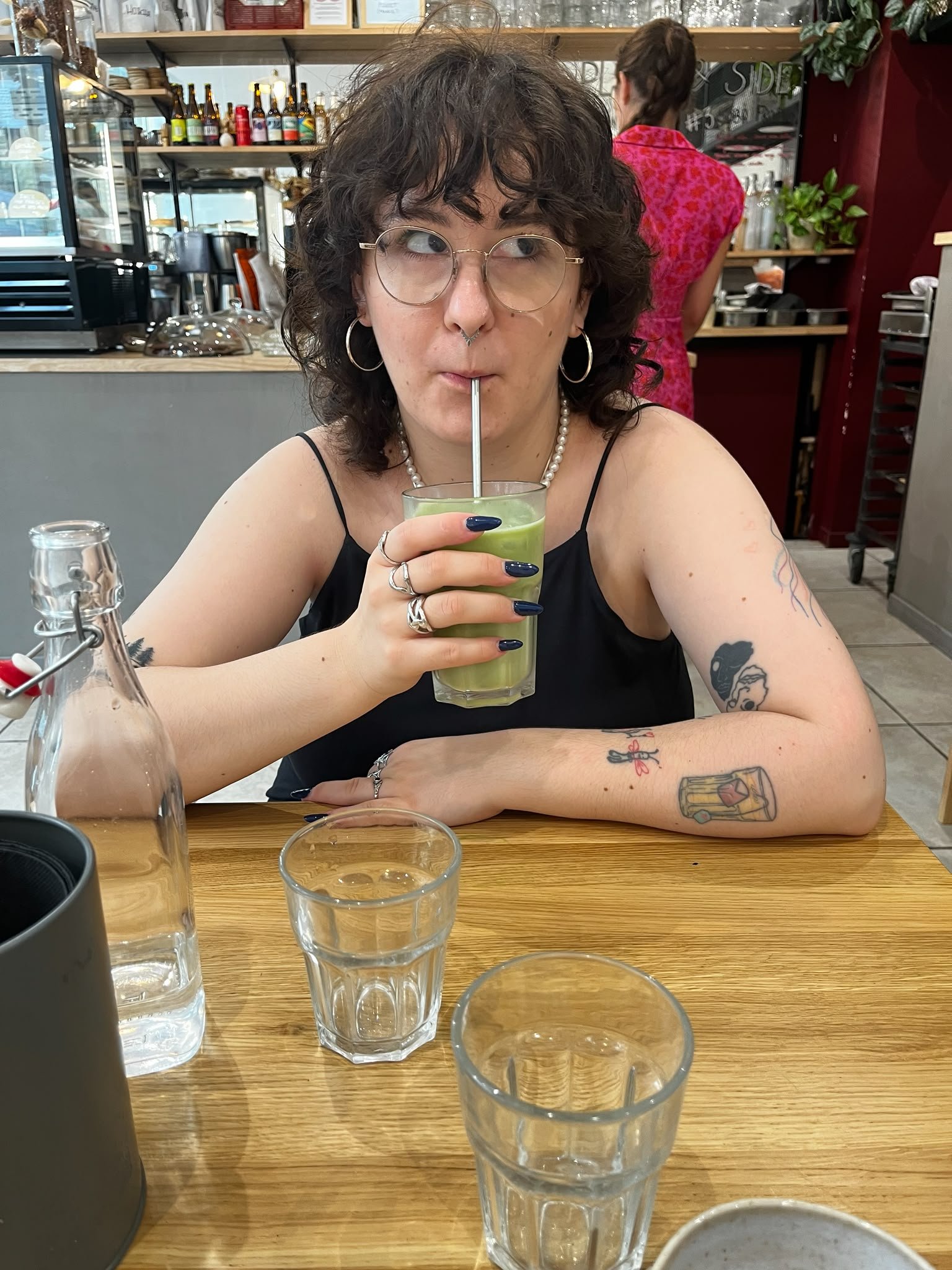 Dominika, Squarespace web designer at Pretty Online Club, sitting at a café table drinking an iced matcha latte