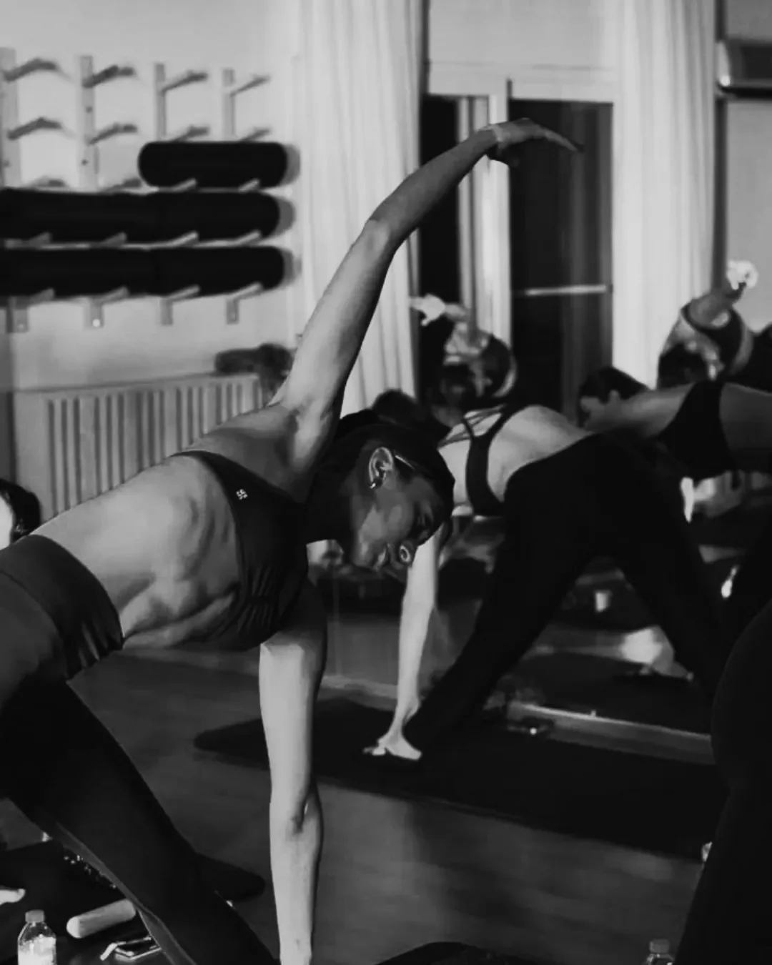 People practicing yoga in a studio, performing a side stretch pose.