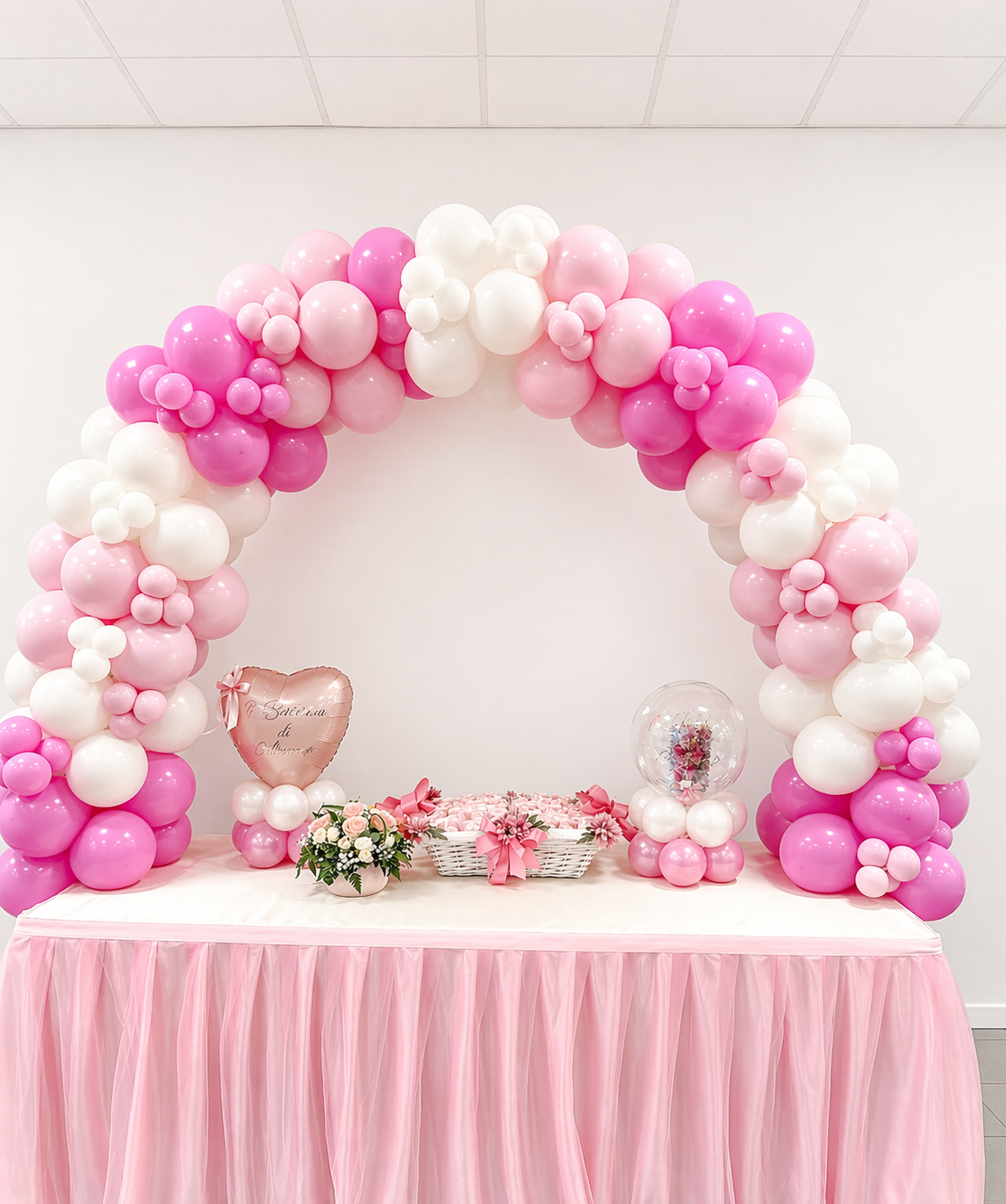 Allestimento con arco di palloncini su tavolo a Bologna con decorazioni rosa e dettagli floreali