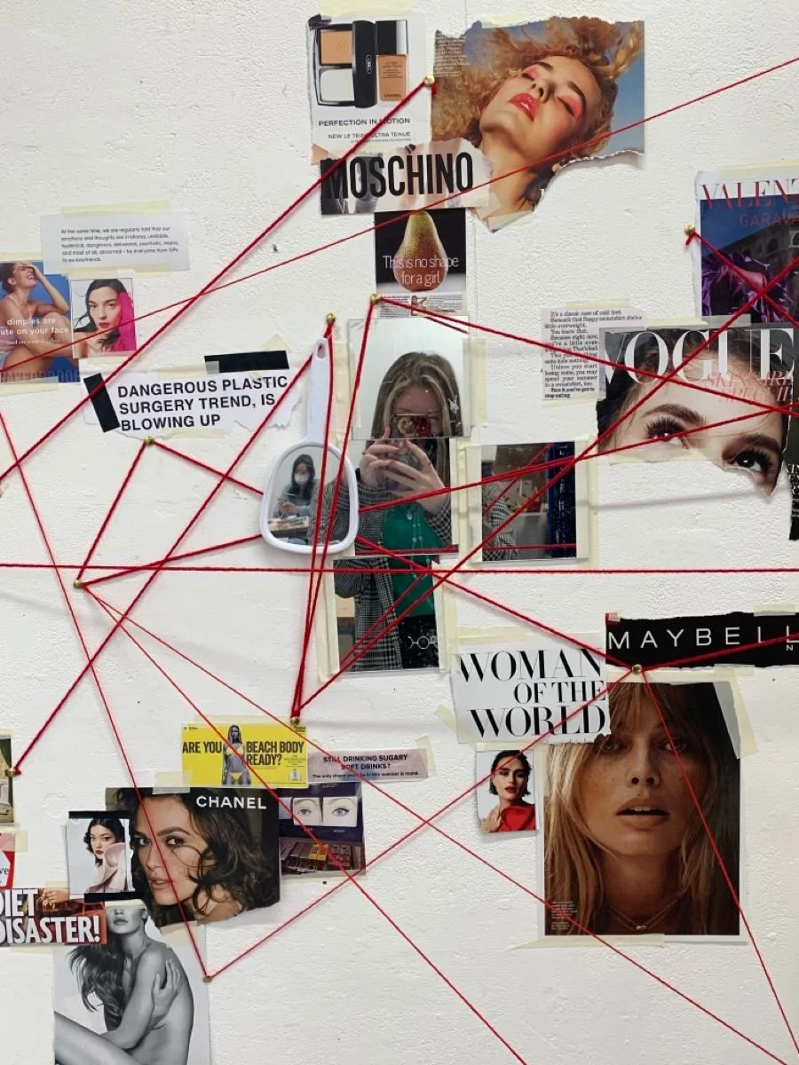 A collage on a wall with magazine clippings, photographs, and notes connected by red string, suggesting an investigation or conspiracy board. The images feature women, makeup products, and headlines about plastic surgery and beauty trends.