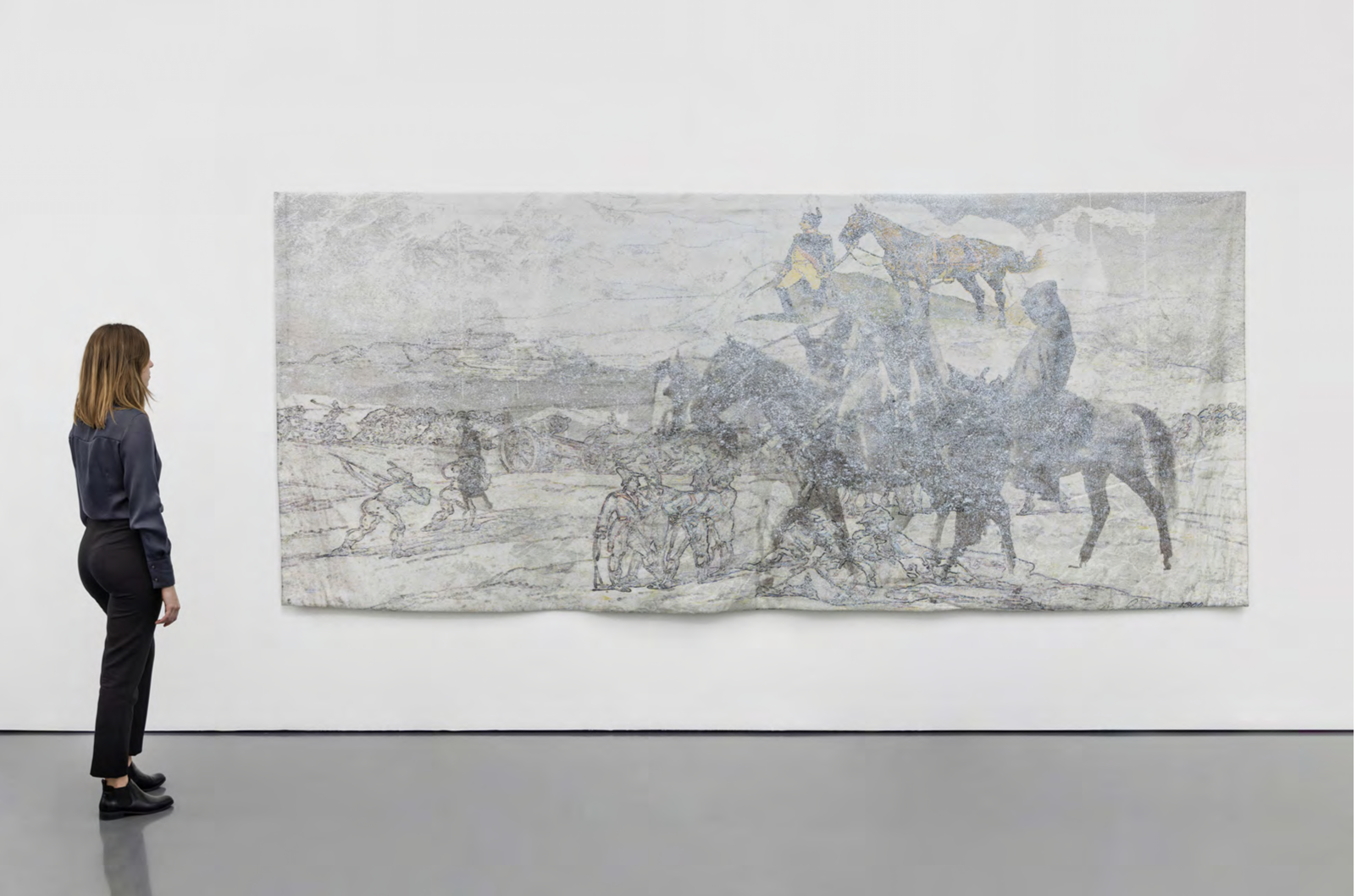 A woman in black pants and a dark blouse looking at a large abstract painting on a white gallery wall.