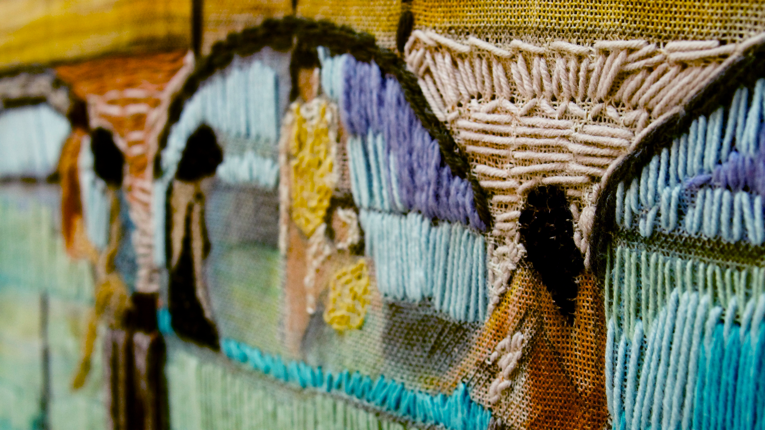 Close-up of a woven textile with colorful, textured threads forming a pattern.
