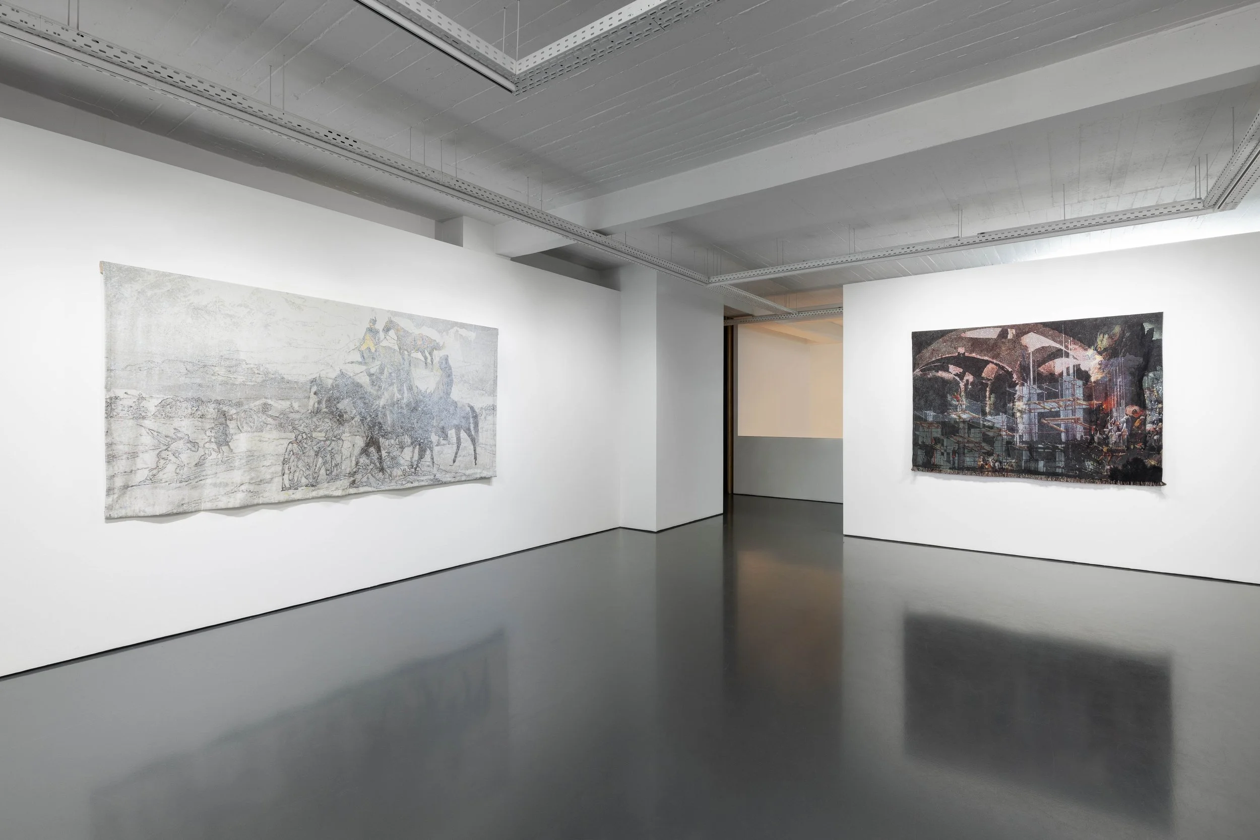 A modern art gallery with white walls displaying two large abstract paintings. The gallery has a polished gray floor and a ceiling with exposed ducts and lighting.