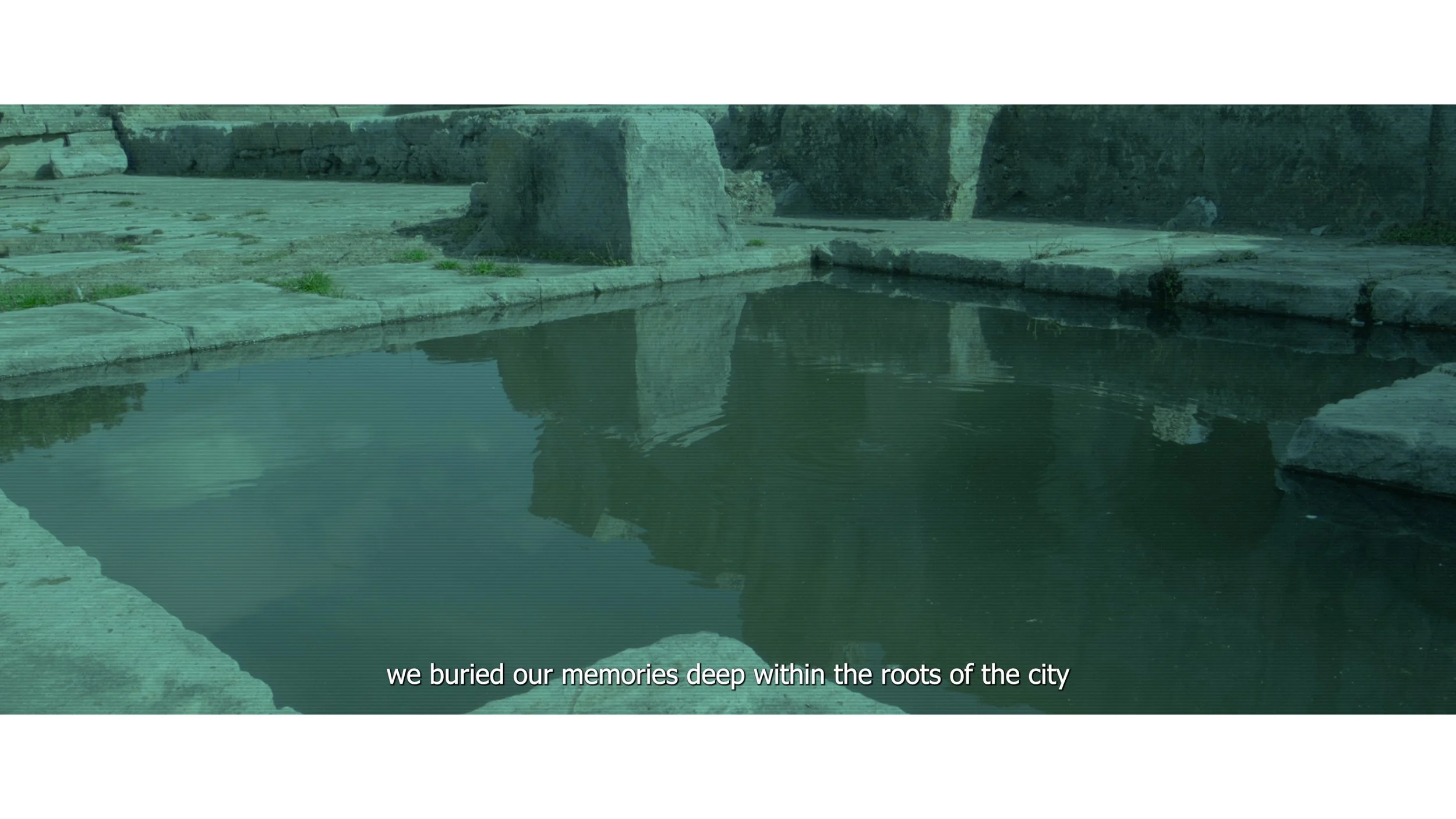 A narrow river or canal lined with stone and concrete, with large rocks and debris along the banks, and a partially submerged object in the water, with a caption reading 'we buried our memories deep within the roots of the city'.