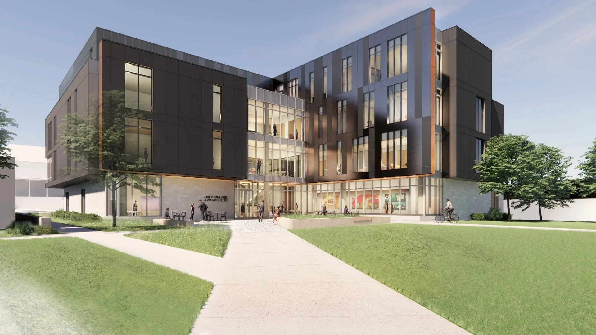 A modern multi-story academic building with black and gray exterior panels, large glass windows, and a landscaped front with pathways, trees, and outdoor seating, with people walking and cycling outside.