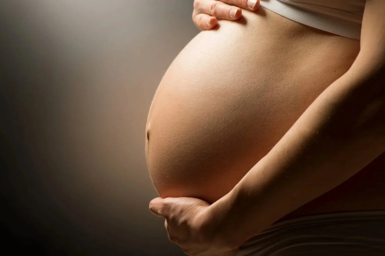 ventre de femme enceinte dans une lumière chaude pour illustrer un rendez-vous afin de rédiger un projet de naissance
