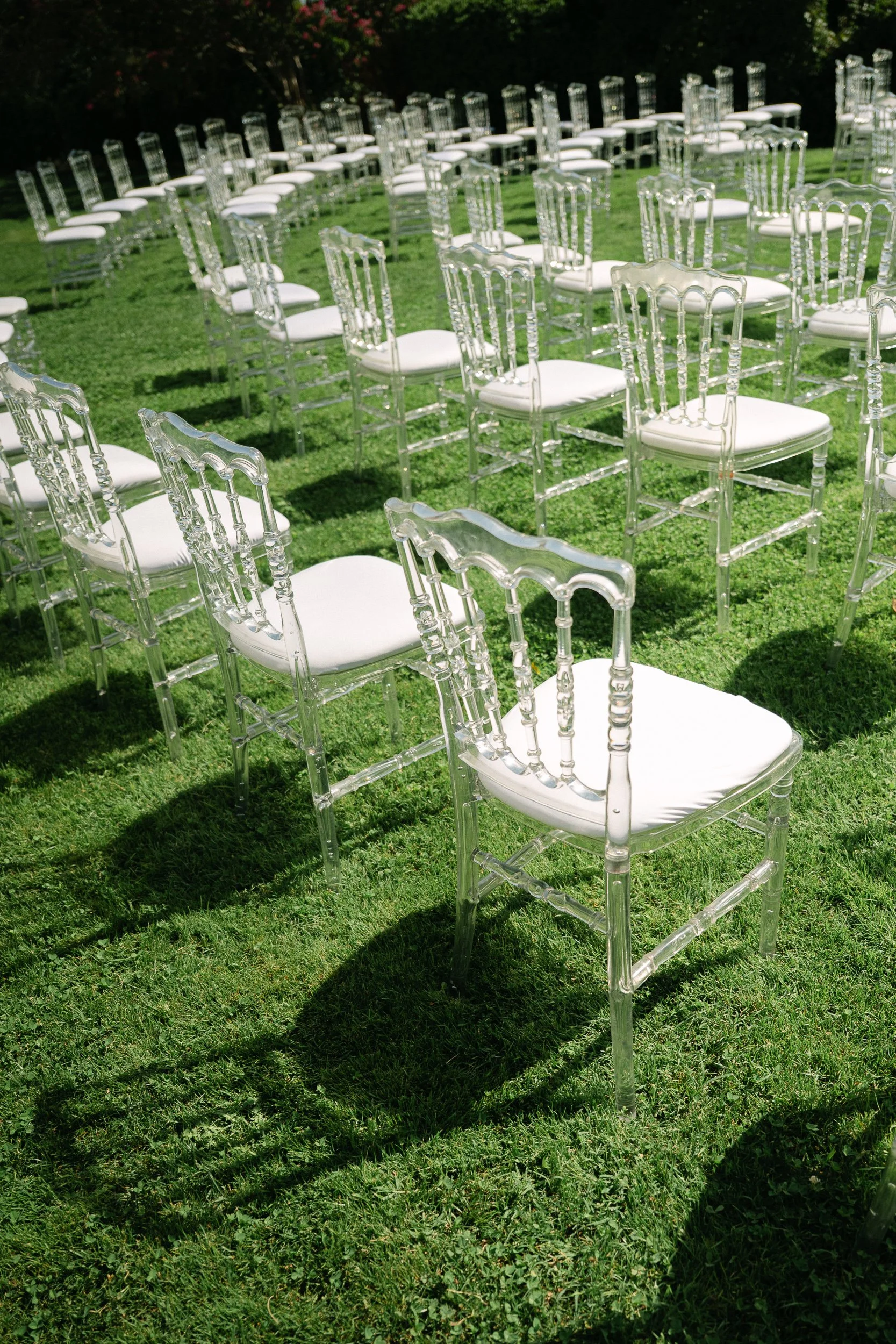 Rows of clear chairs set out on the lawn for an outdoor ceremony at Château Fengari
