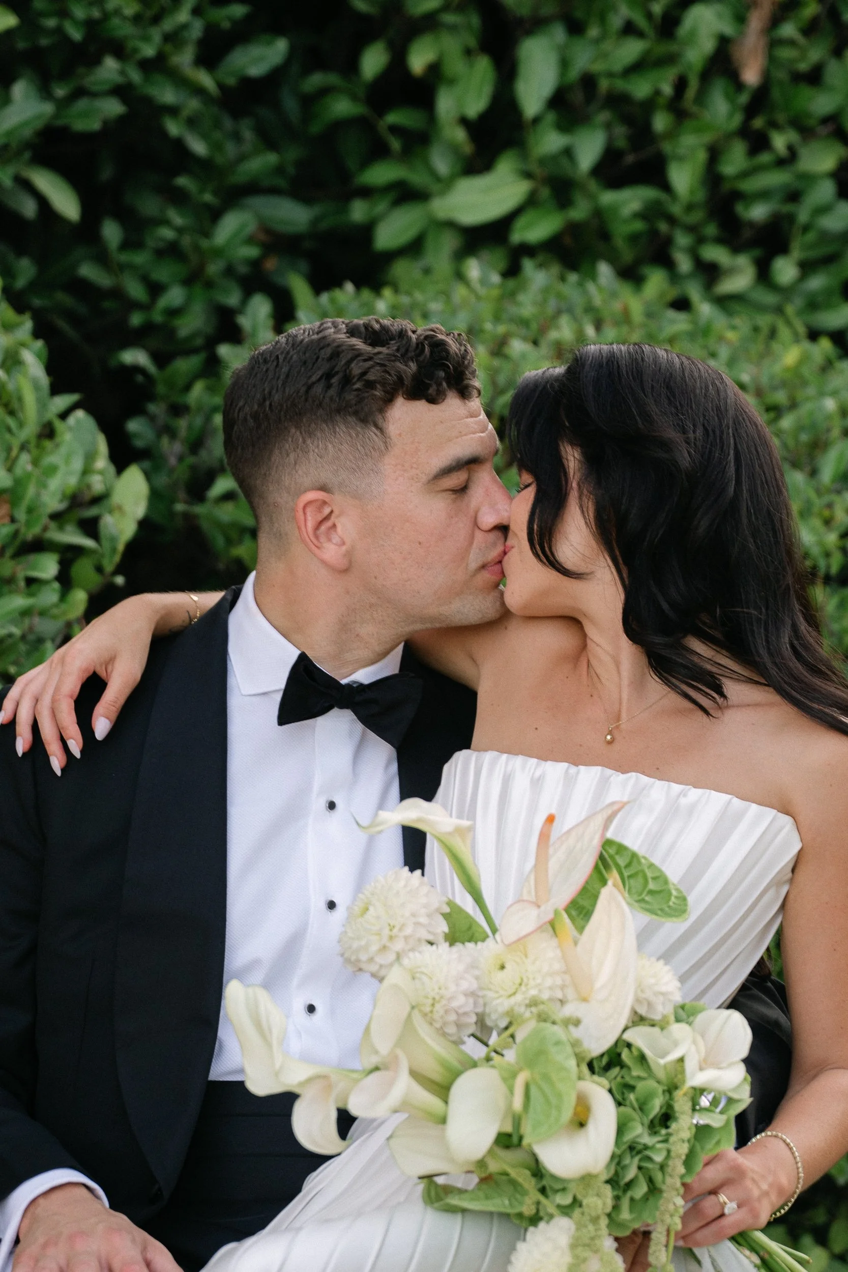 Bride and groom kissing after the ceremony, surrounded by greenery at Château Fengari