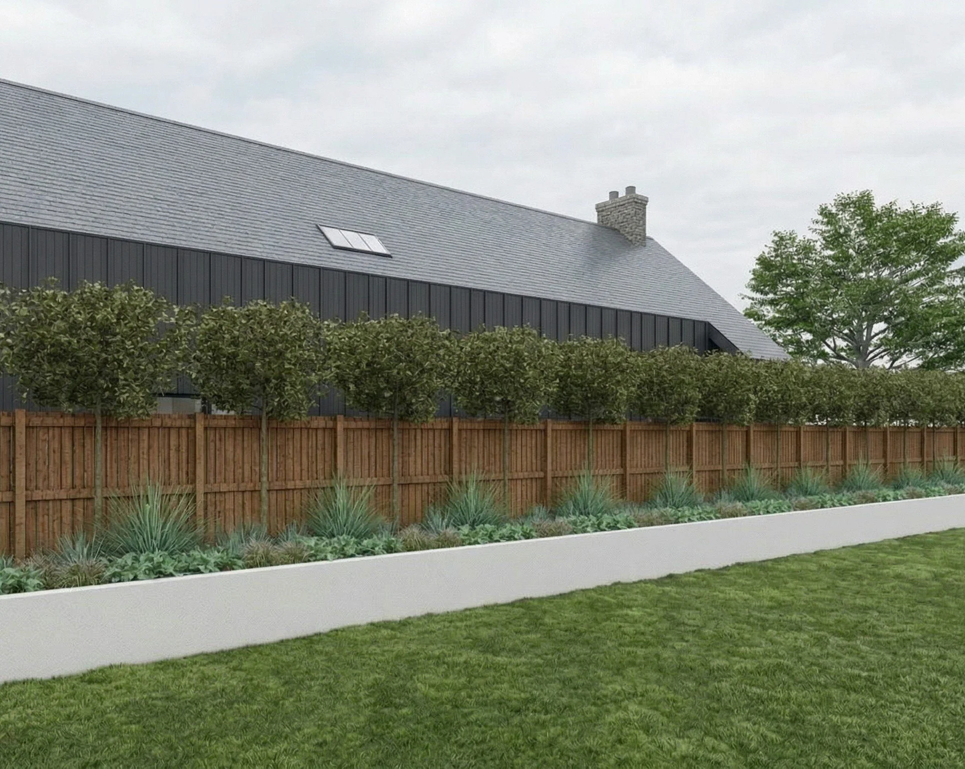 View of a modern house with a gray roof, solar skylight, brick chimney, a wooden fence, and a landscaped yard with green grass, plants, and trees under an overcast sky.
