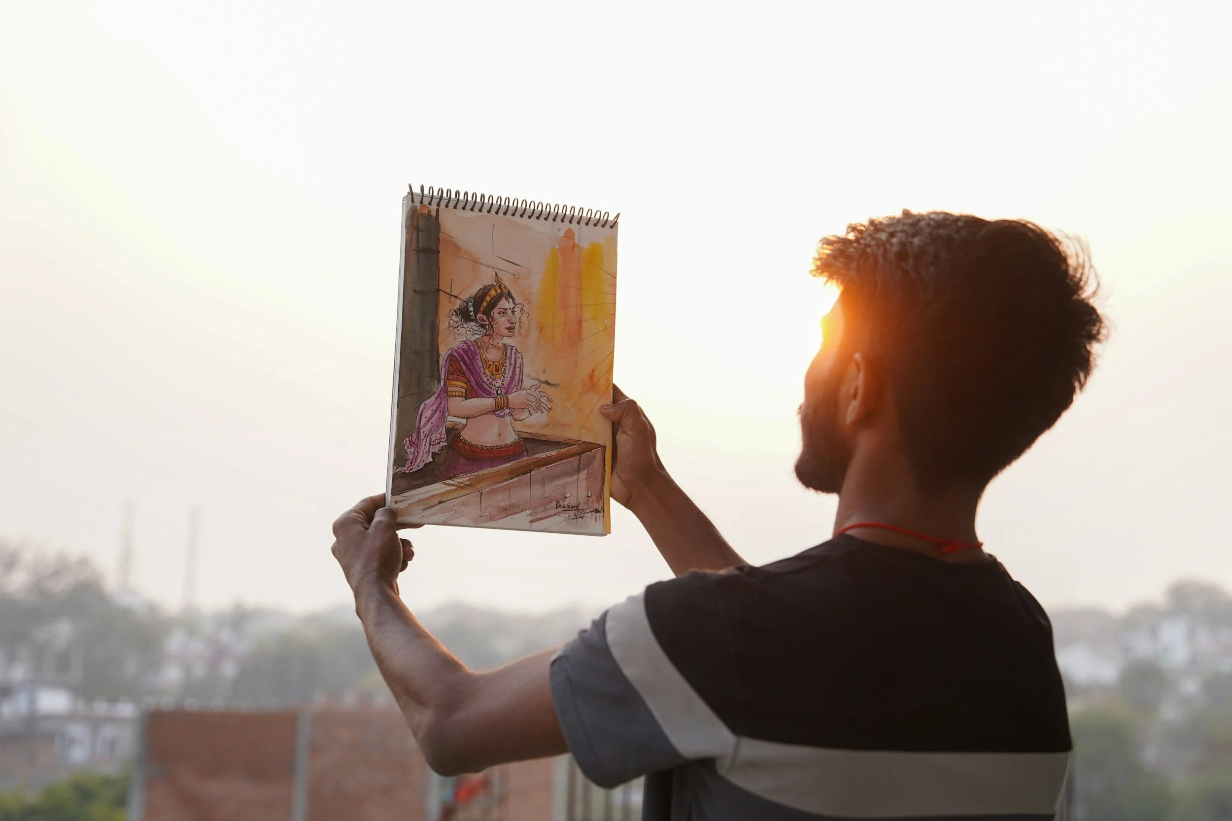 An artist holds up a painting to the light.