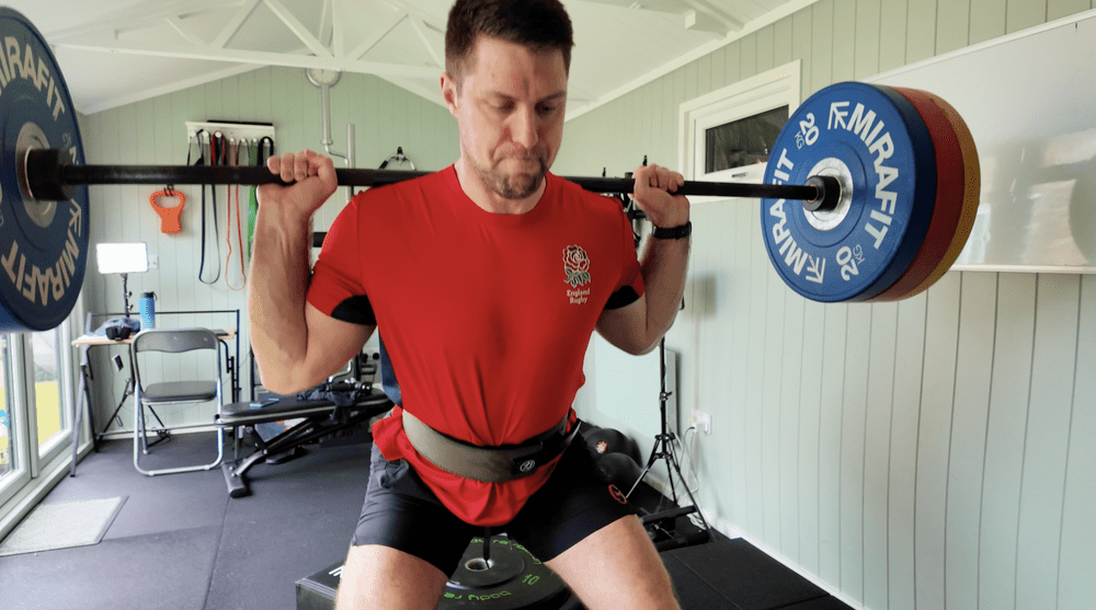Client back squatting in James's private gym
