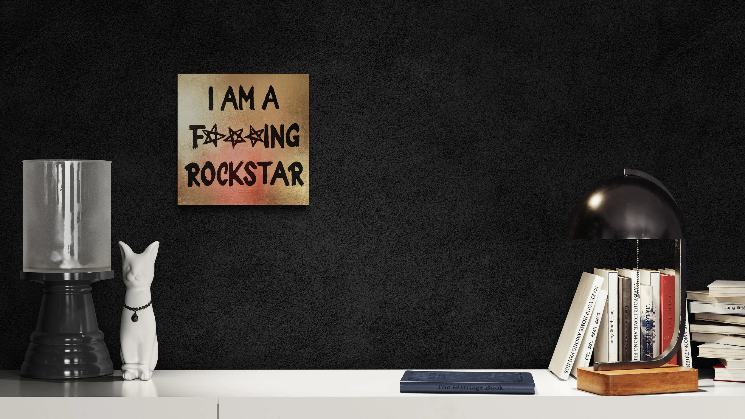 Büroregal mit Büchern, einem schwarzen Schreibtischlampe, einer weißen Katzenfigur, einem schwarzen Kerzenhalter und einer Wanddekoration mit dem Schriftzug 'I AM A F***ING ROCKSTAR' auf schwarzer Wand.