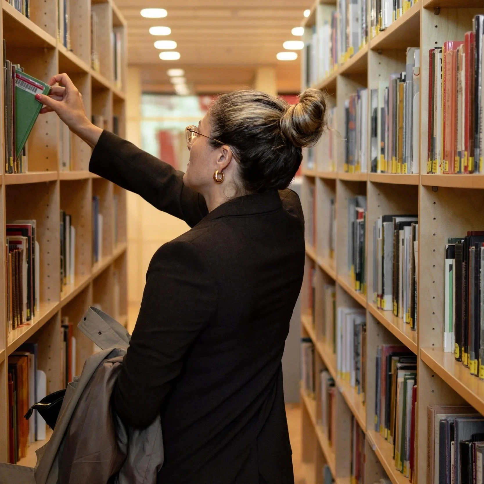Amina Siječić Selimović velger en bok fra en bokhylle ved Universitetet i Oslo.