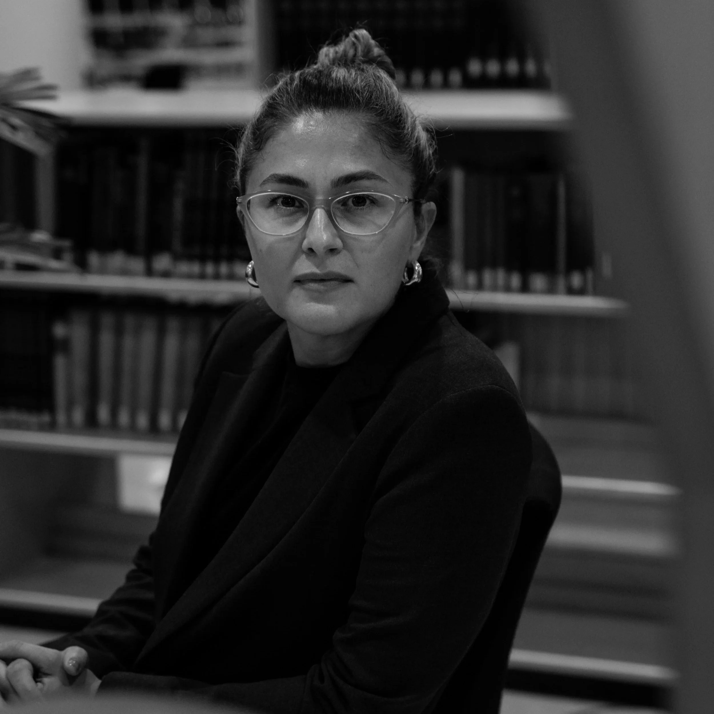 Svart-hvitt-portrett av Amina Siječić Selimović foran bokhyller ved Universitetet i Oslo.