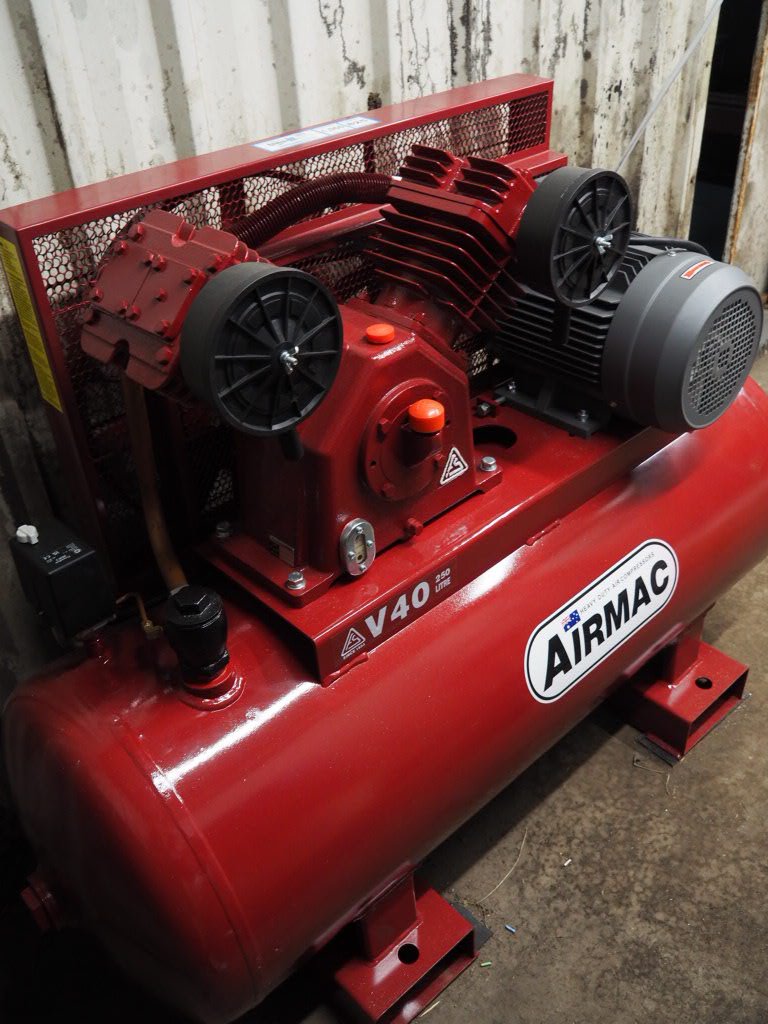 Red air compressor with black motor and dual cylinders, labeled 'AIRMAC V40 200'.