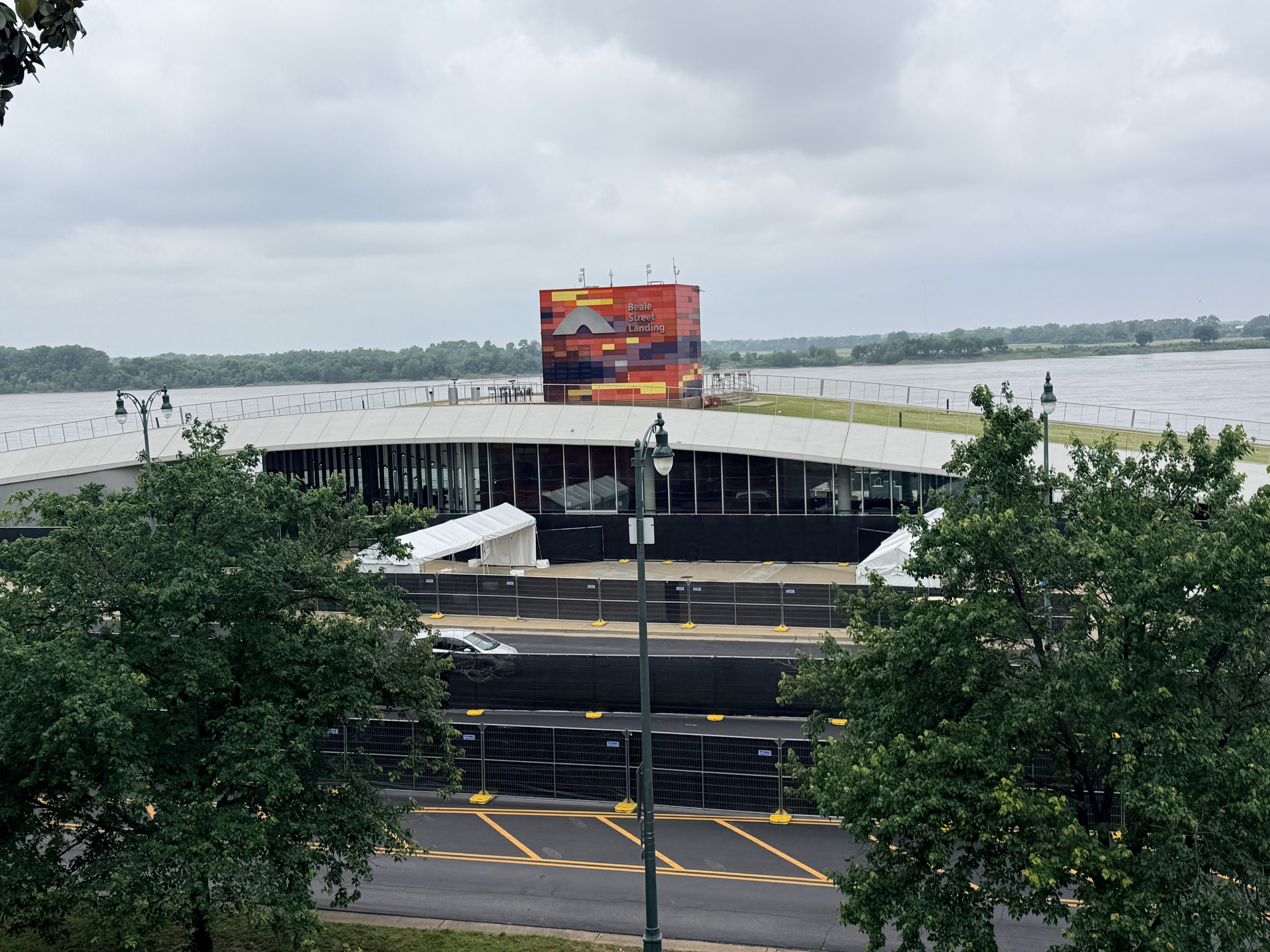 View of Beale Street Landing overlooking the river, with cloudy sky and trees in the foreground.