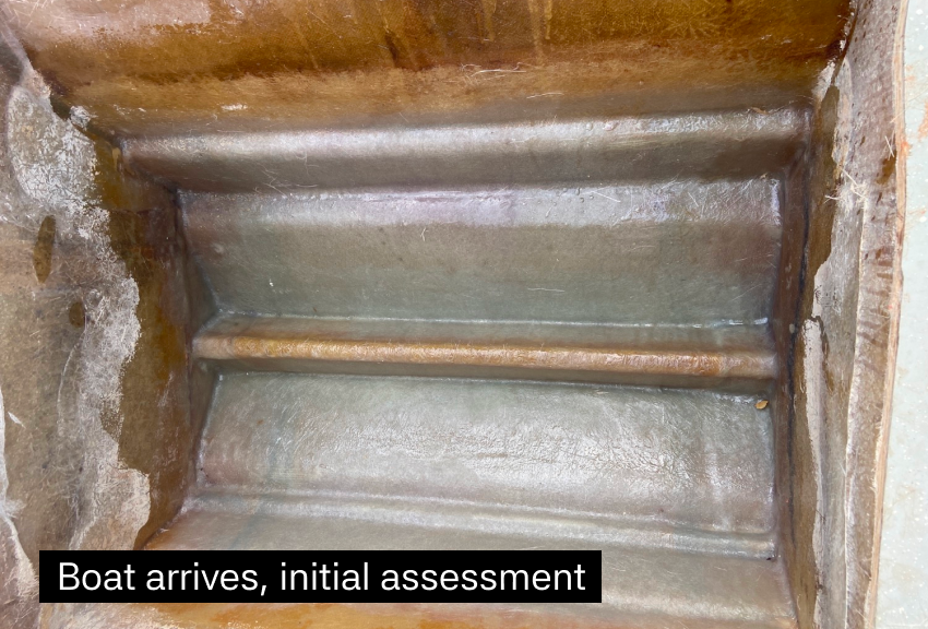 Inside a rusty metal boat with a wet surface, possibly during initial assessment after arrival.