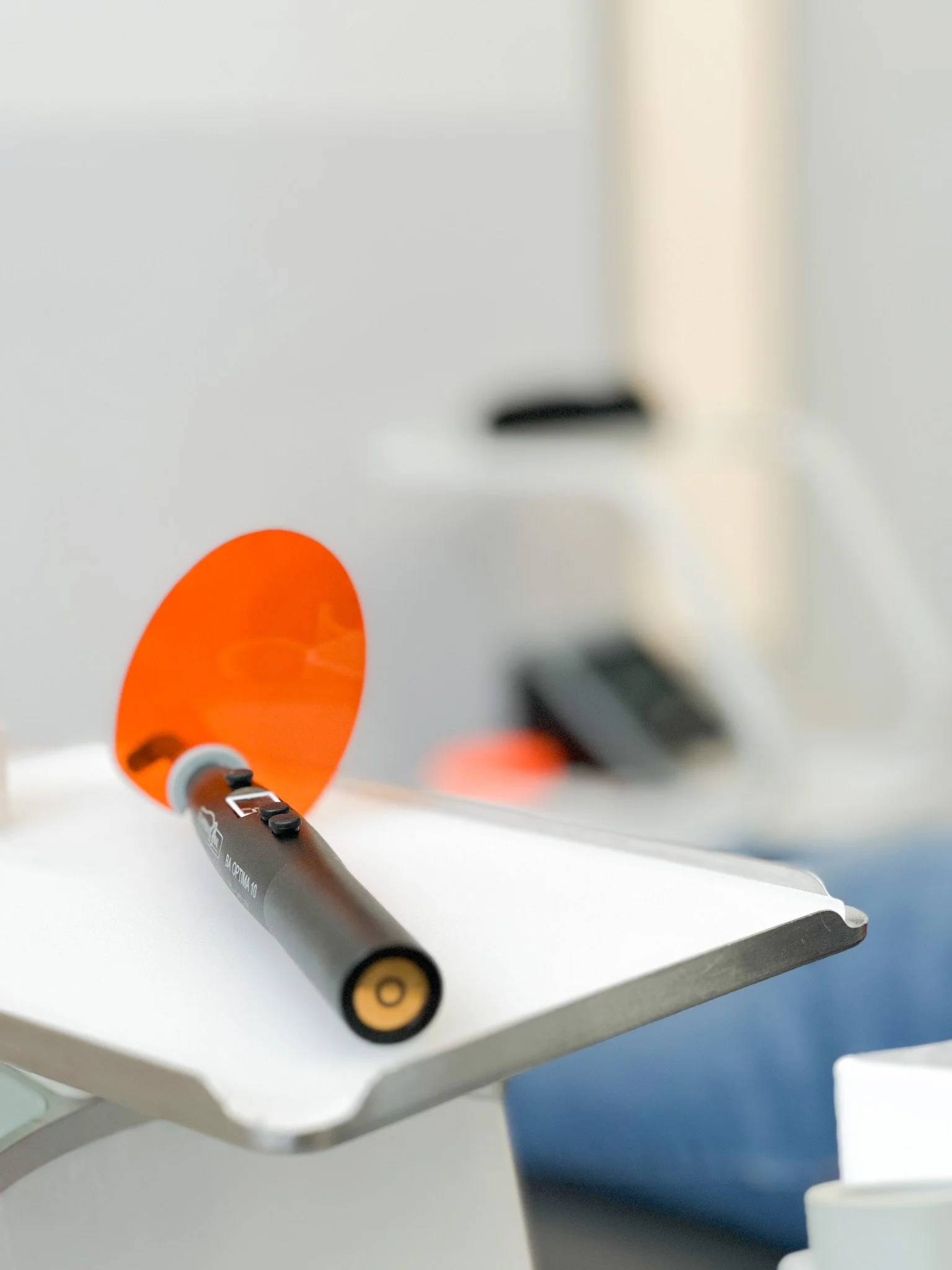 un stylo noir posé sur un support blanc avec un fond flou comprenant un objet noir et un mur clair