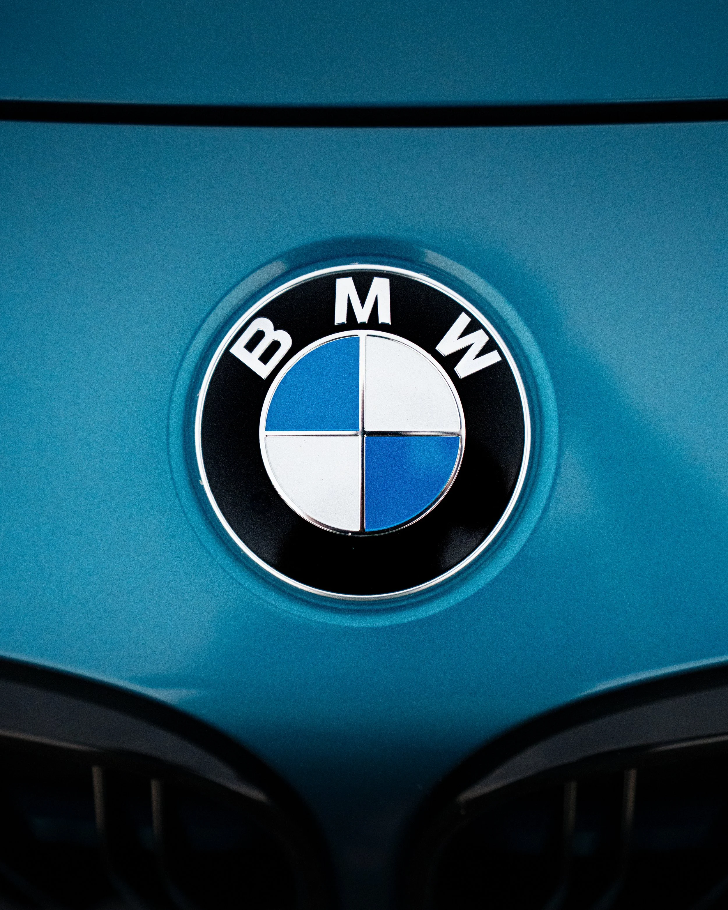 Close-up of a BMW logo on a blue car, with the front grille in the foreground.