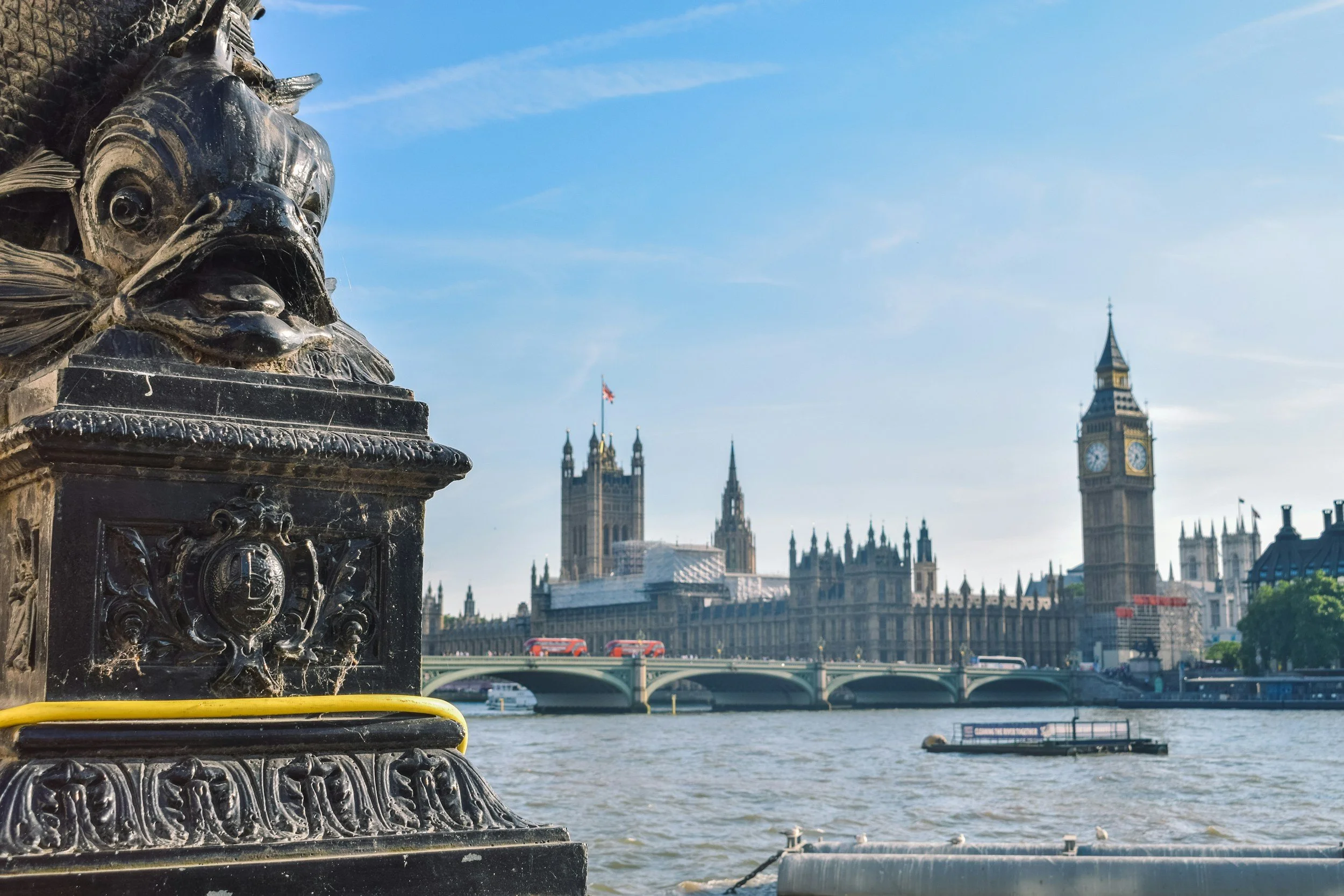 The London skyline including the Big Ben clock tower and Westminster Abbey in the background, along the River Thames.