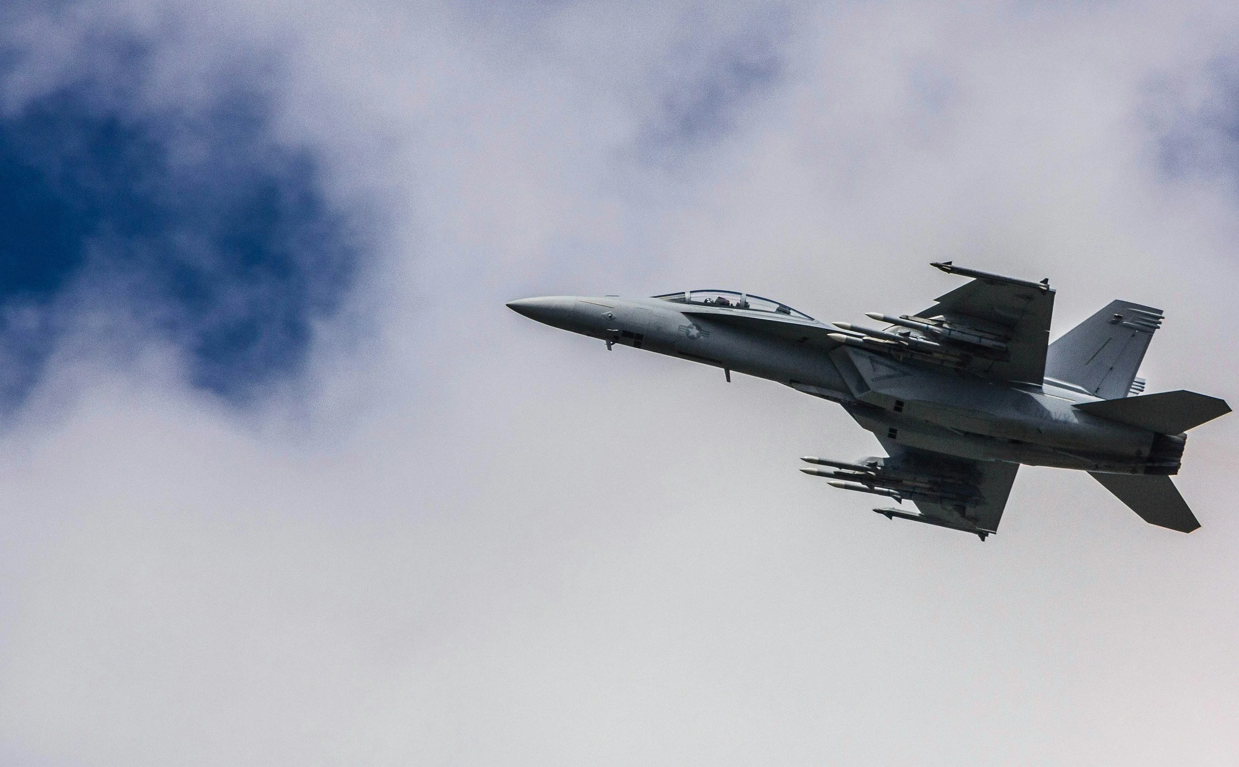A fighter jet flying through cloudy sky.