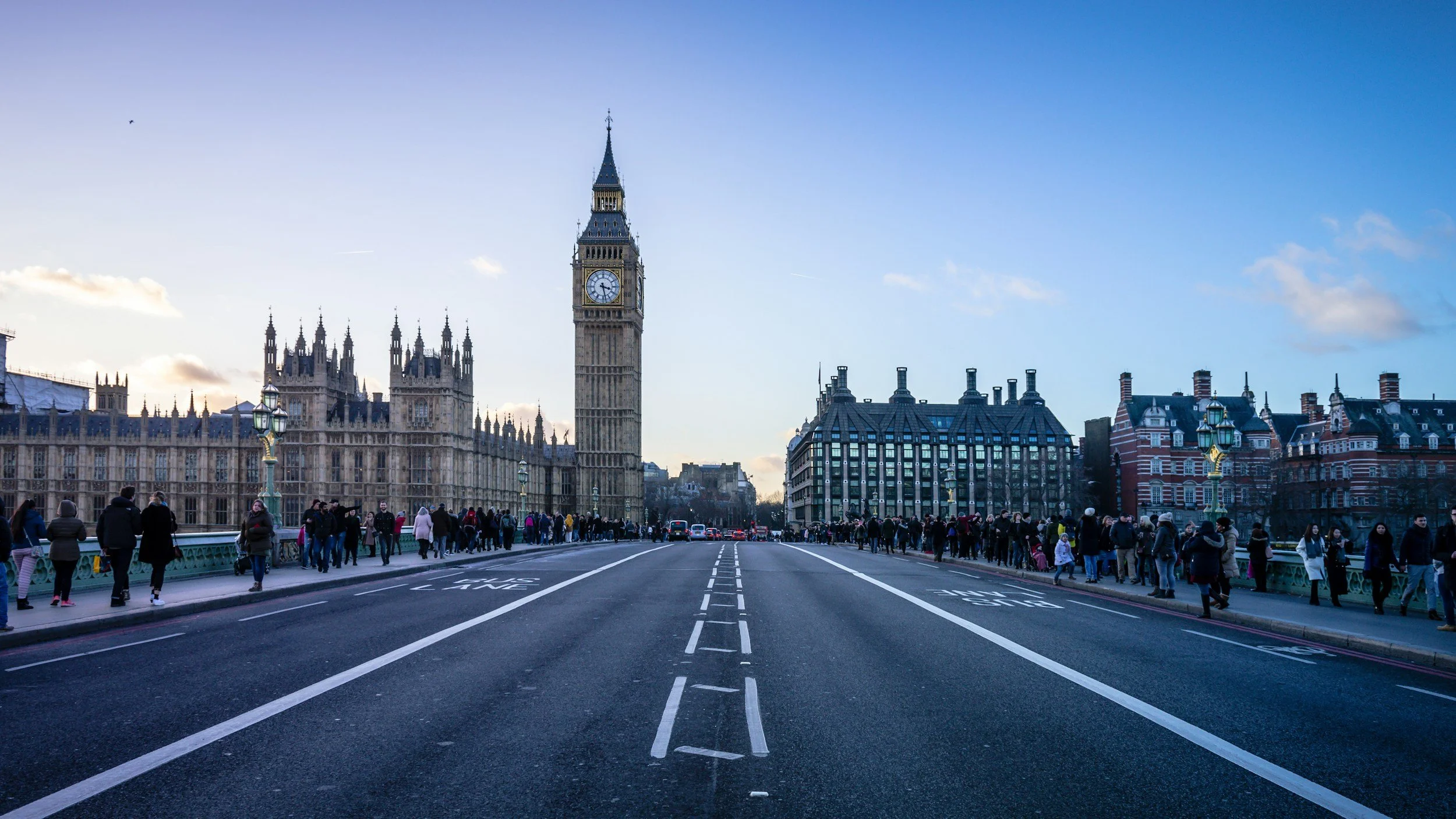 People walking on a bridge with the Elizabeth Tower (Big Ben) in the background, in London, England.