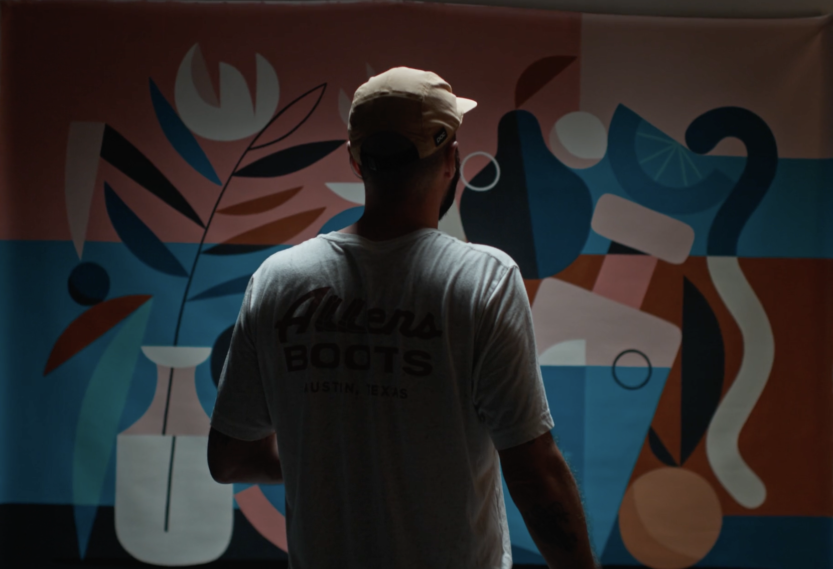 Artist Ruben Sanchez with his back to the camera as he looks at  one of his abstract, colorful still life paintings. Part of Zozi Art Gallery's inaugural exhibition, Presence.