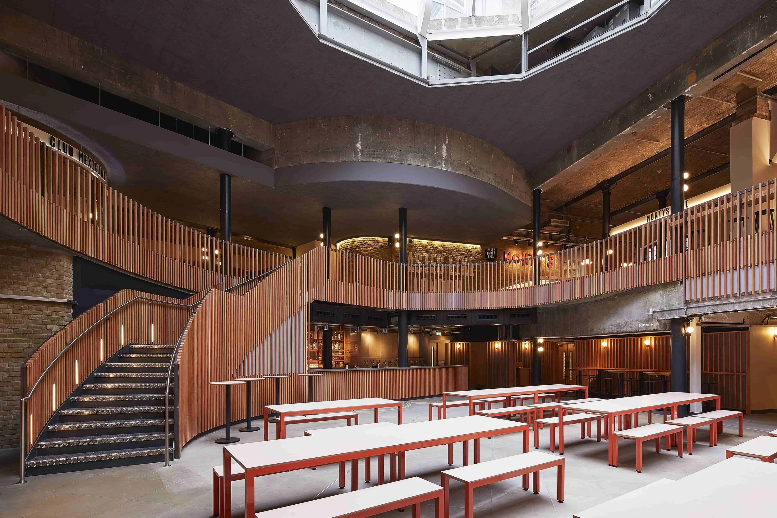 Interior of a modern, multi-story commercial building with wooden railing, metal stairs, and open ceiling design.