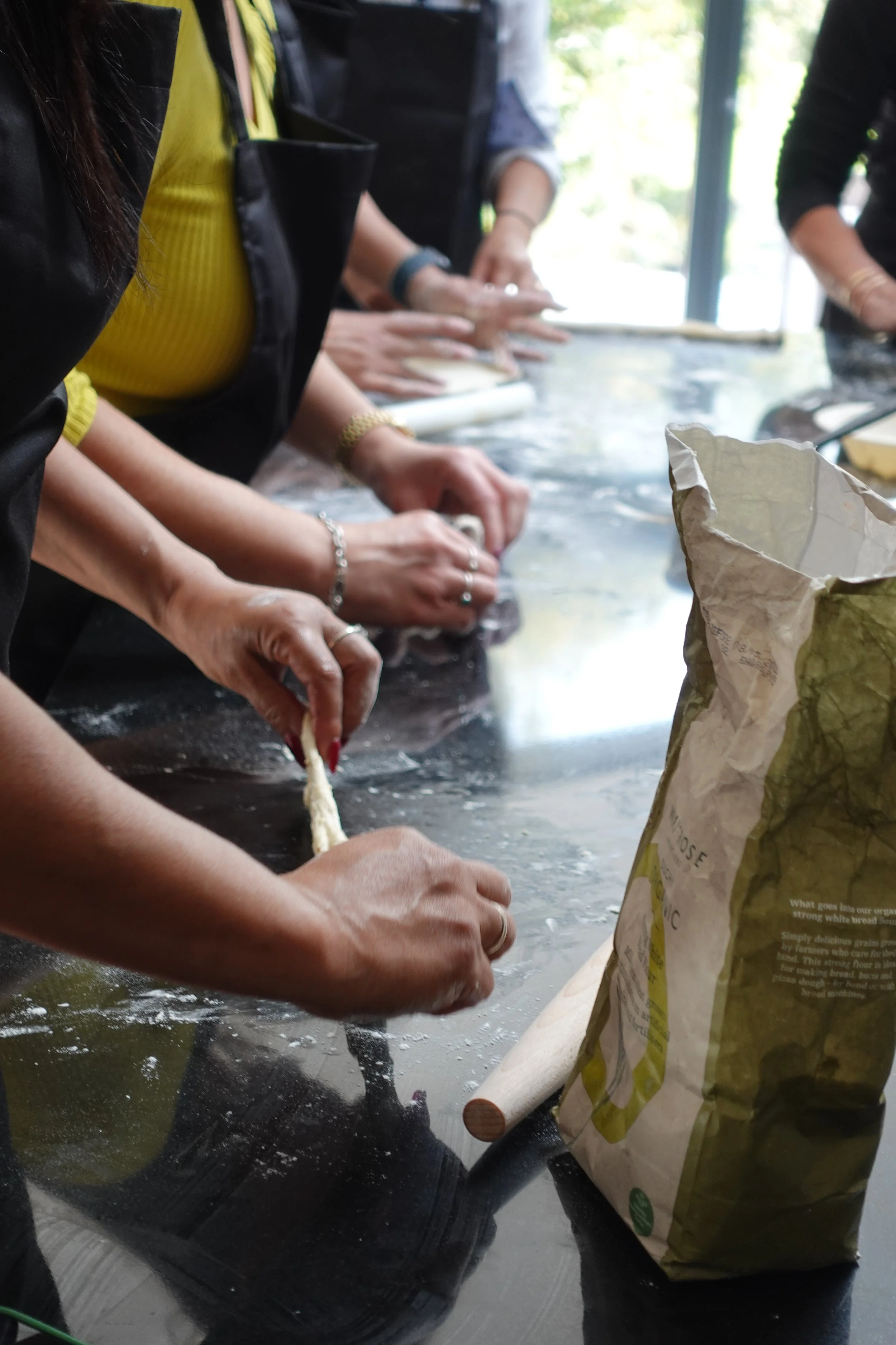 People participating in a baking or cooking class, working together around a table with flour and baking supplies.