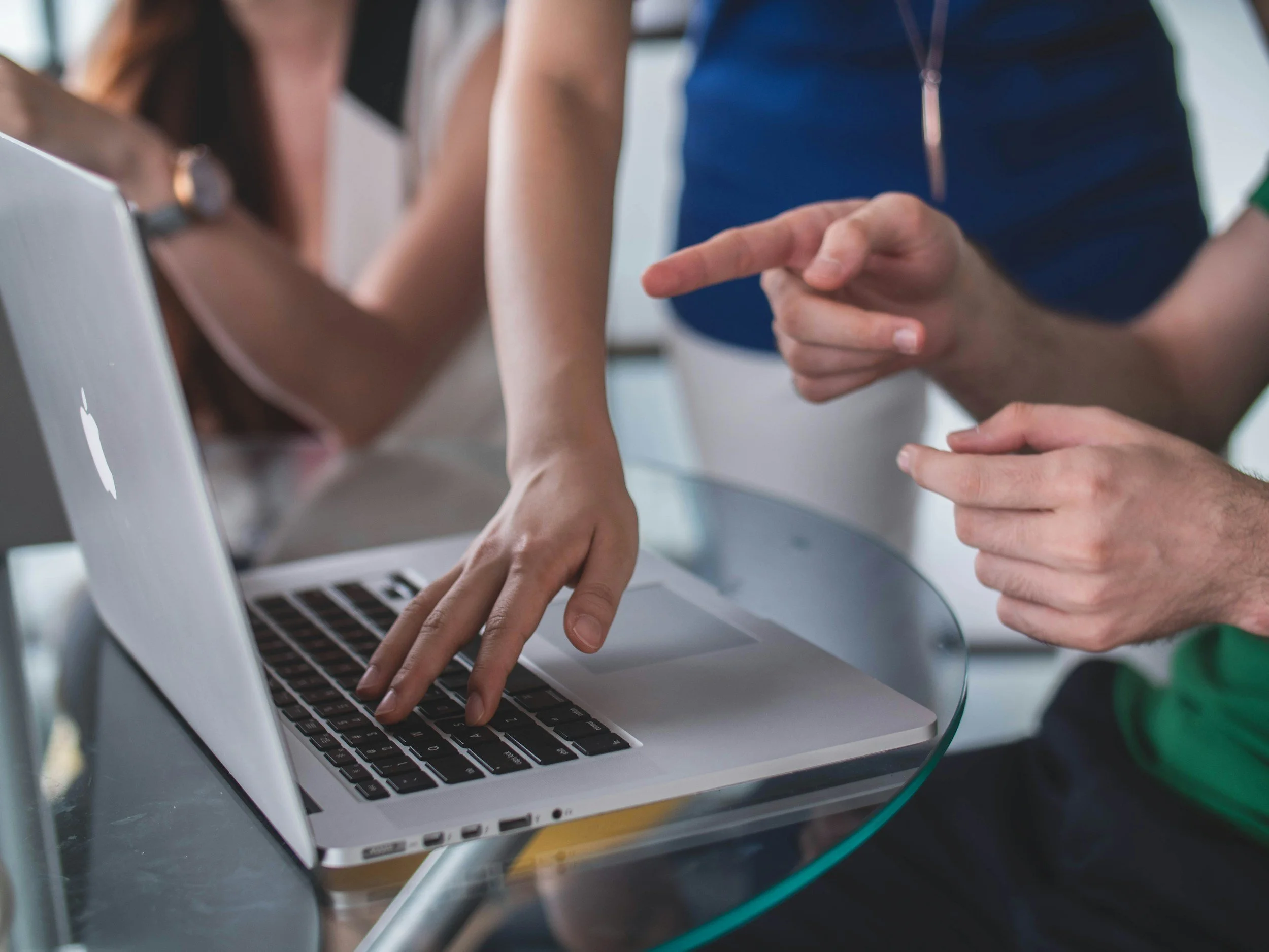 People collaborating on a laptop, pointing and working together.
