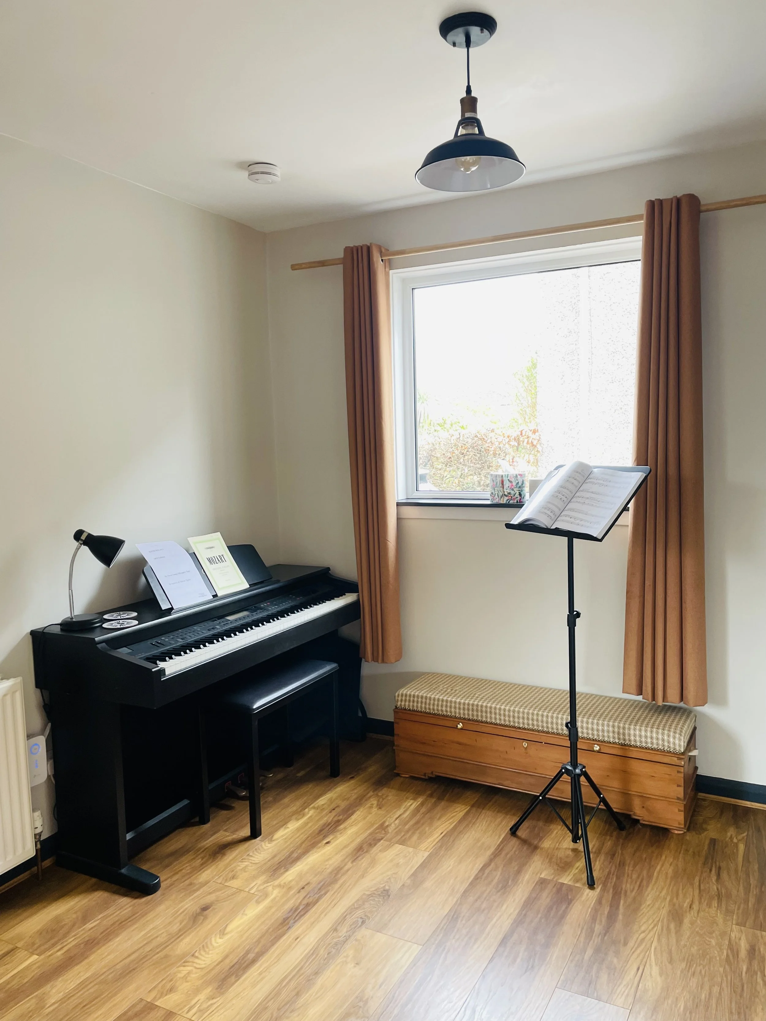 Vocal teaching room with piano, music stand, wooden floors, and window used by Lesley Buchan for singing lessons