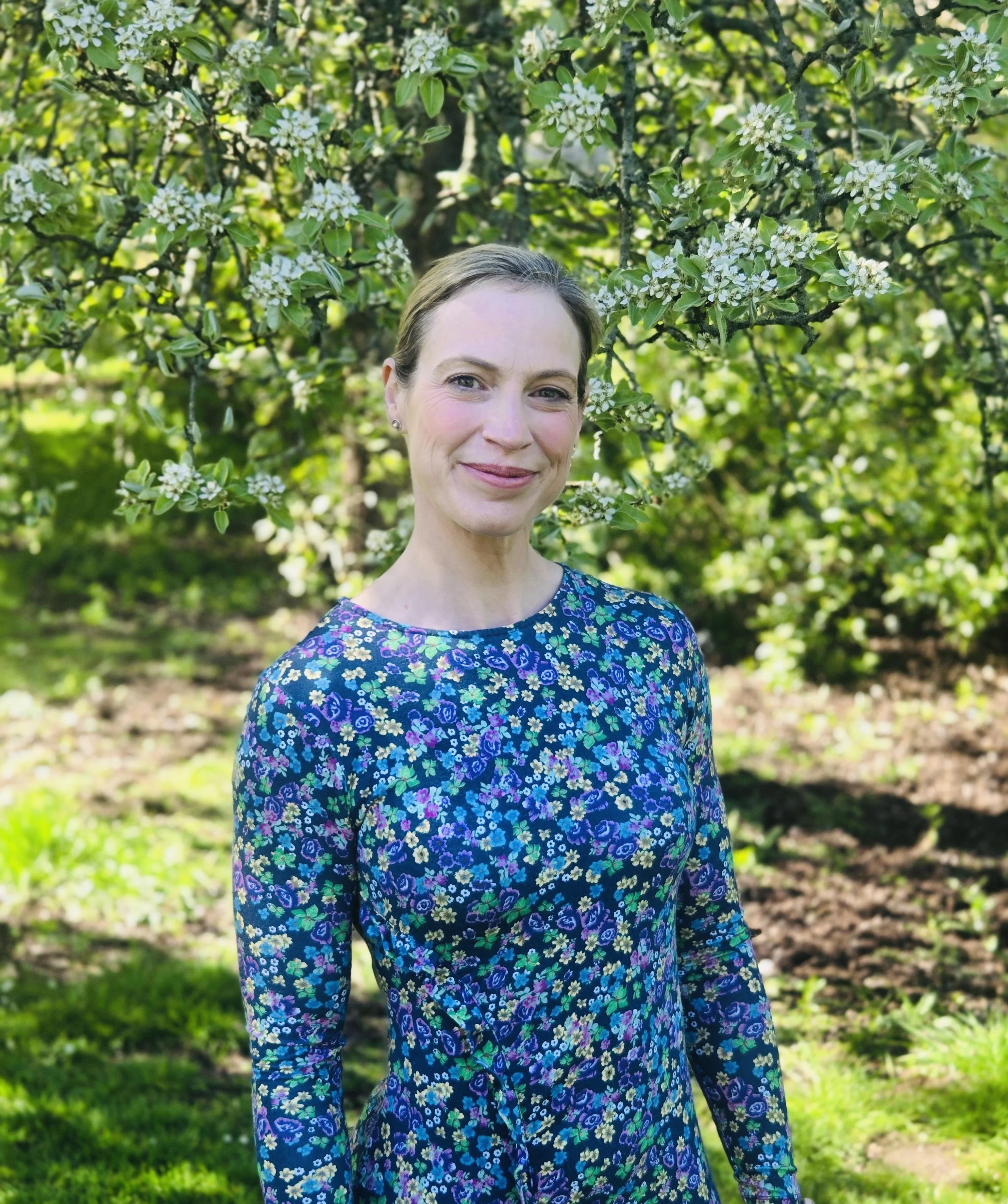 Portrait of Lesley Buchan, soprano and vocal tutor, facing forward in front of flowers