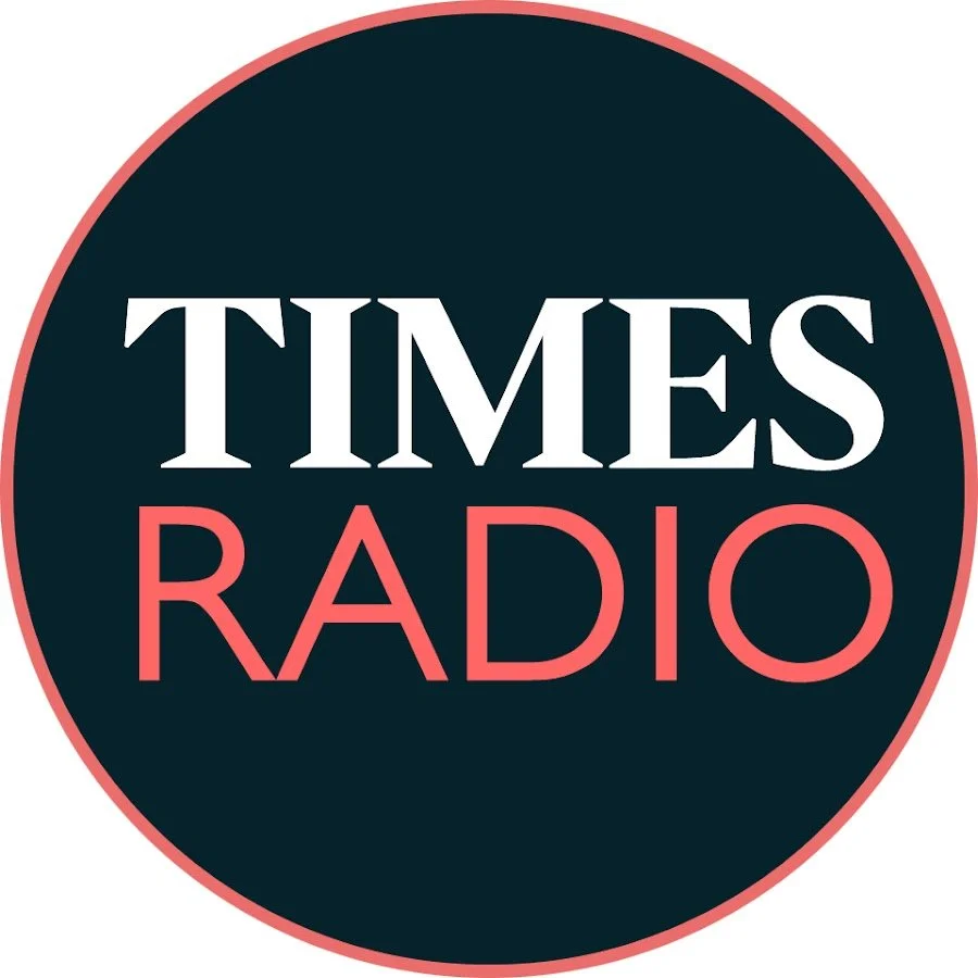 Logo of Times Radio with a dark blue circle, white 'TIMES' text and pink 'RADIO' text inside.