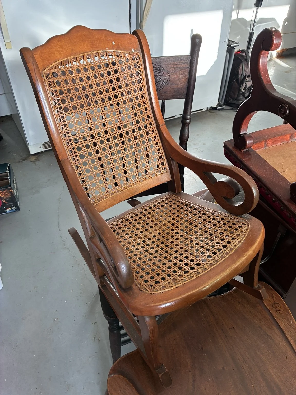 Wooden cane-back chair with a woven seat and curved arms.