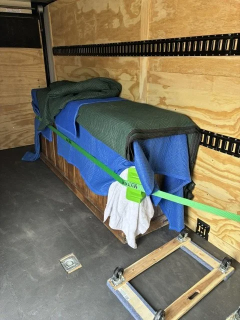 Hand-carved Indian wooden chest blanket-wrapped and secured with a ratchet strap inside Slohaven Transfer's enclosed trailer.