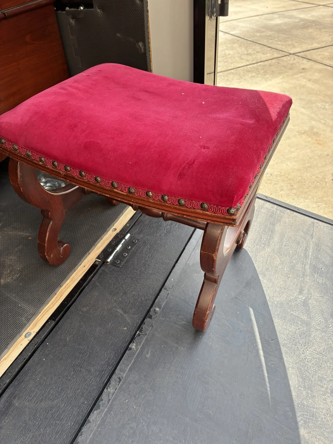 Red upholstered stool with a decorative wooden frame.