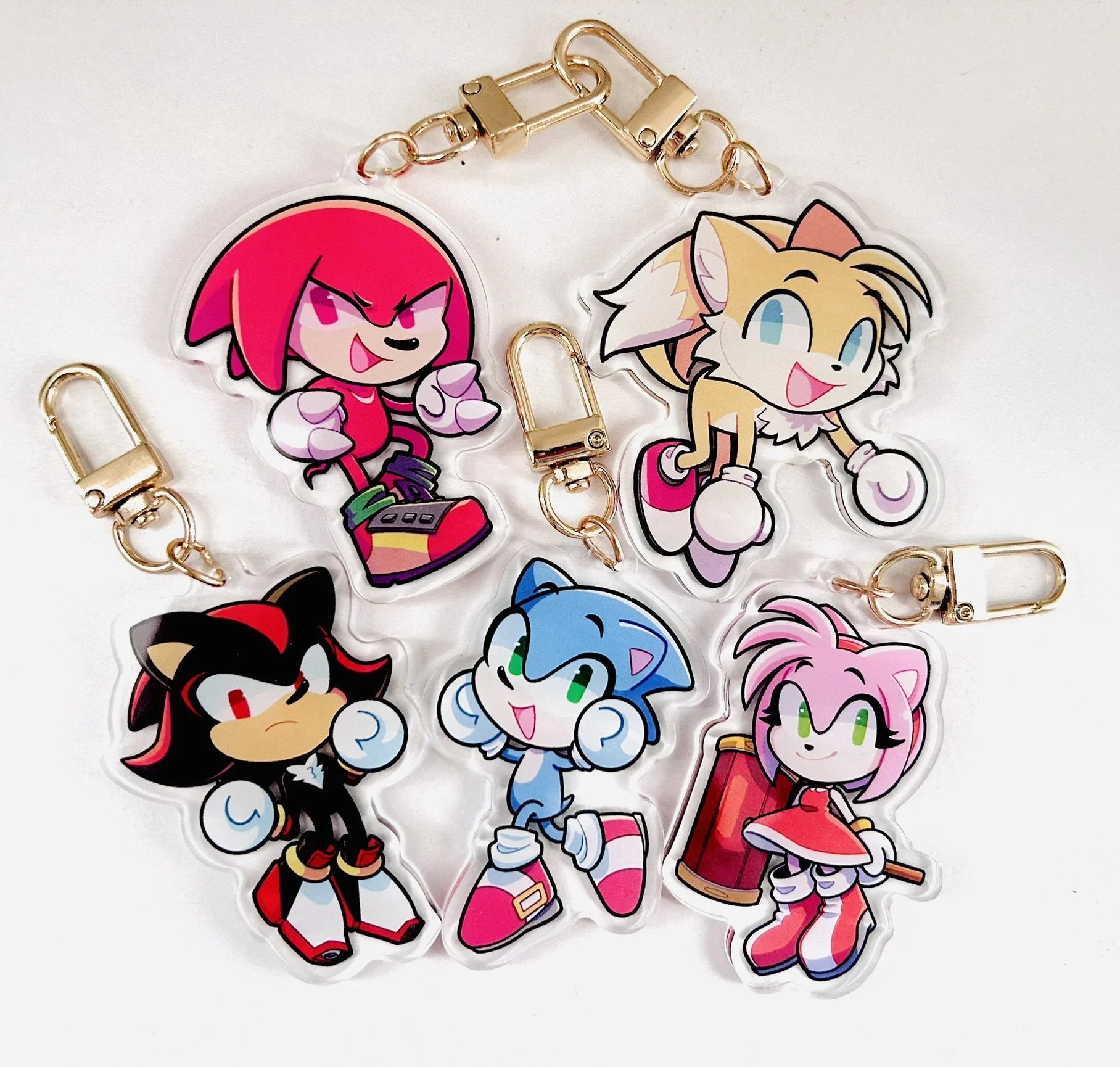 Collection of colorful sonic character acrylic keychains with gold chains and clasps on a white background.