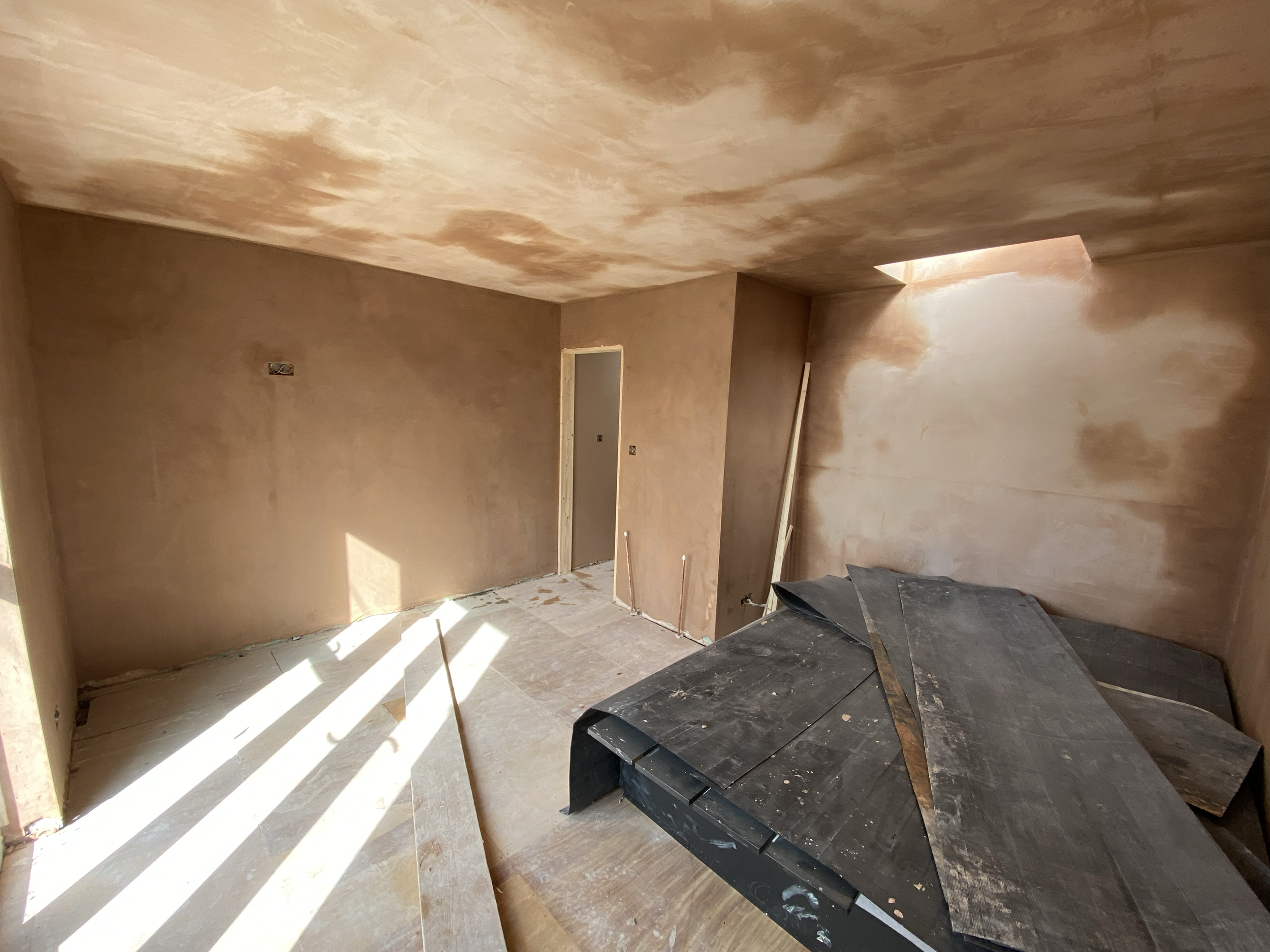 Interior room under construction with unfinished walls and ceiling, some construction materials and tools on the floor.