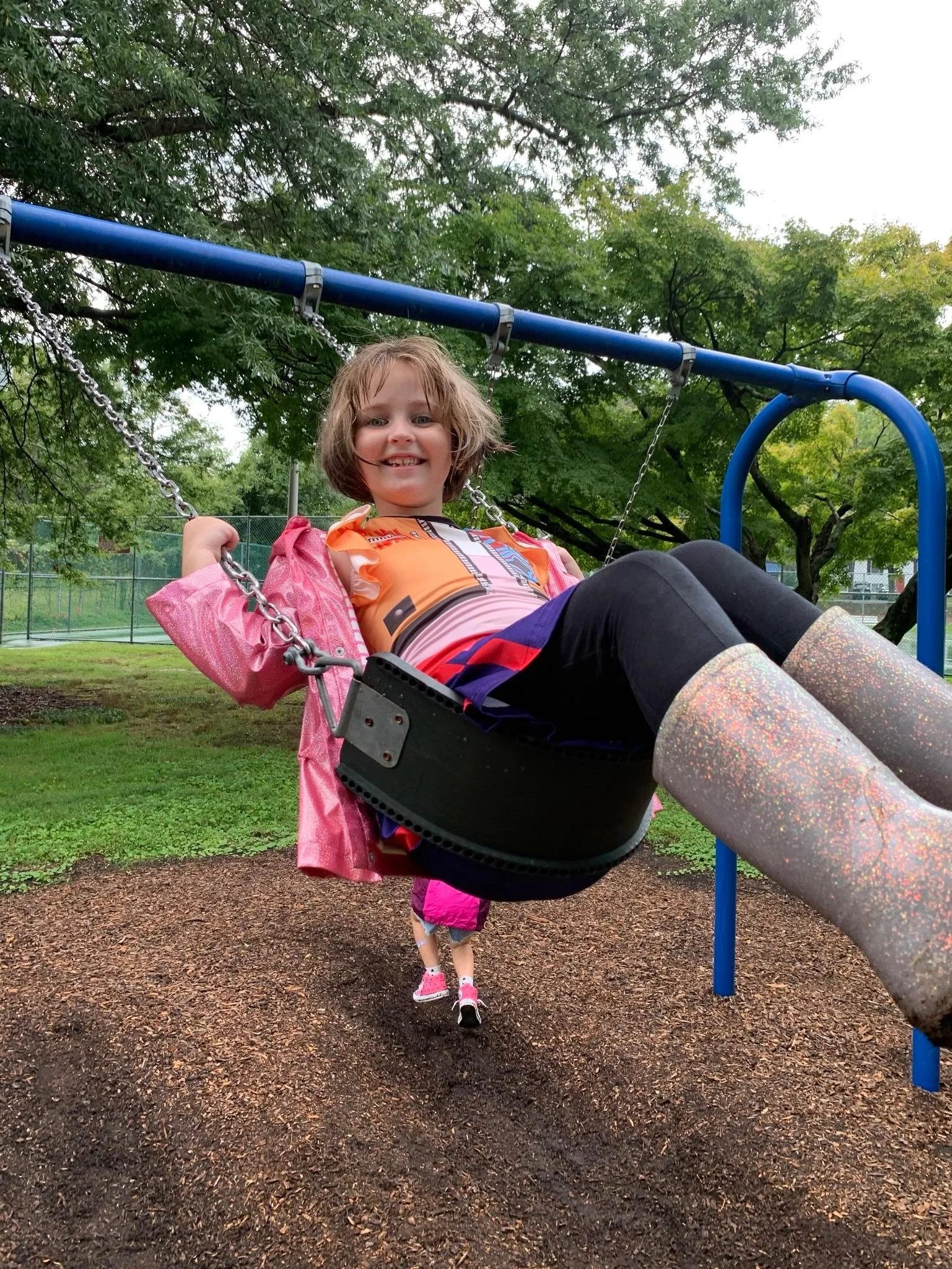 student happily swinging in the rain on a school field trip