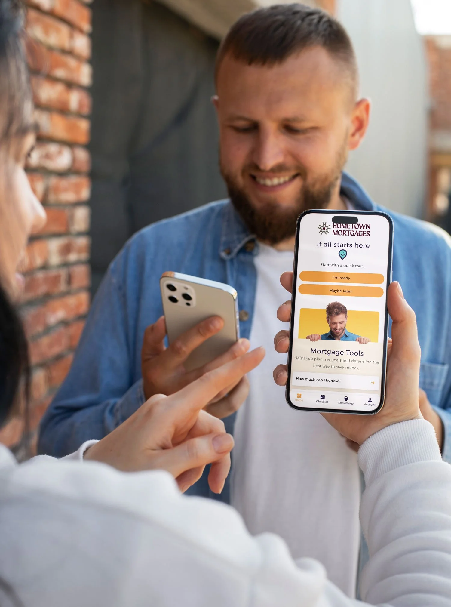 home buying couple looking at hometown mortgages app on iphone