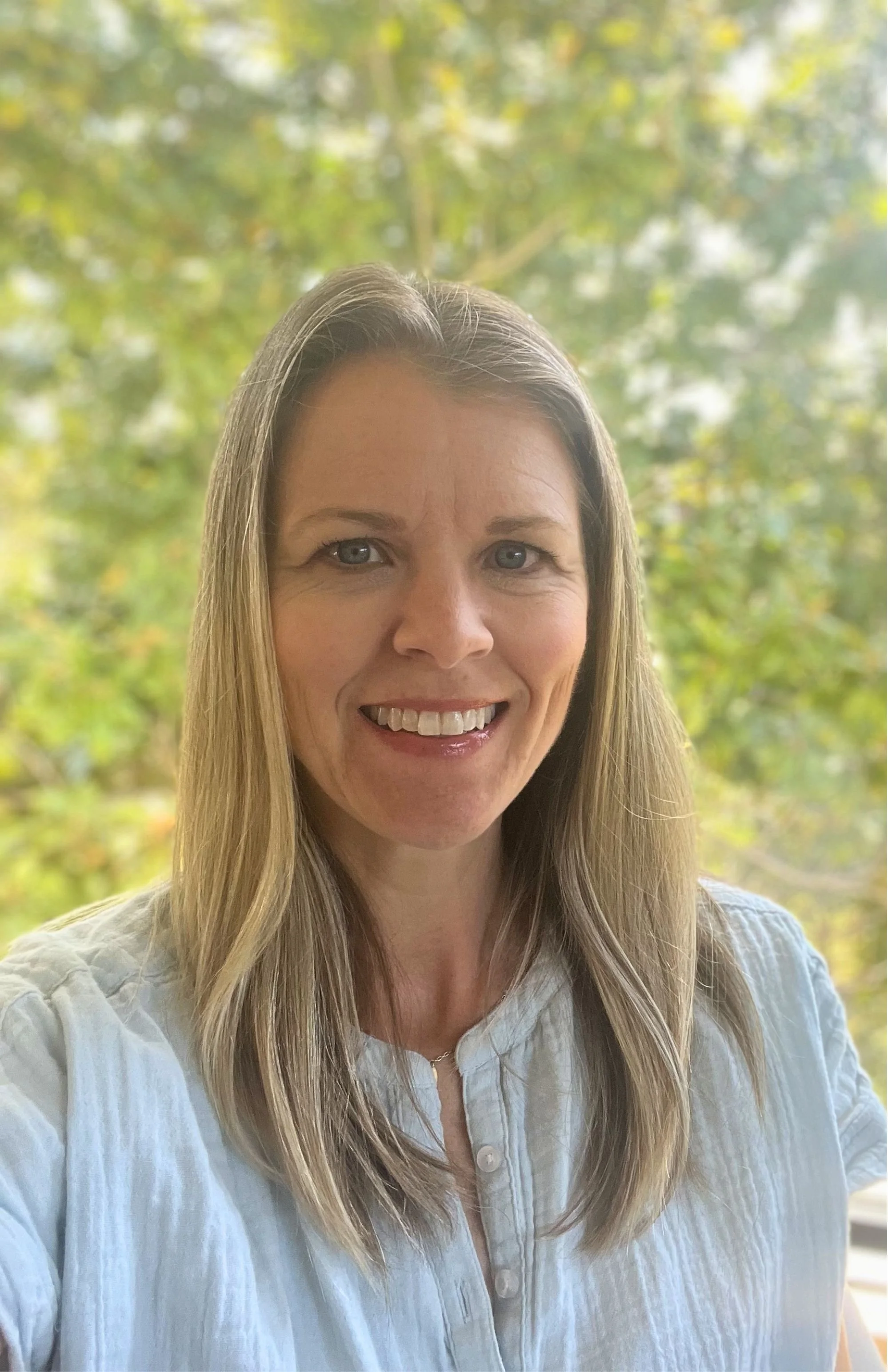 photo of Sarah, smiling with a large magnolia tree in the background