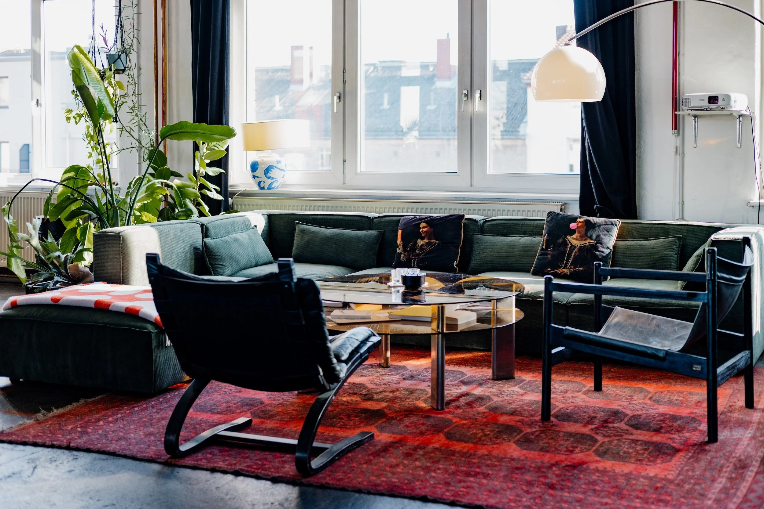 Talk-Formate, Video-Podcasts, Interview-Settings. Das modulare 6-teilige Cord-Sofa (ca. 350 × 200 cm) steht an der Süd-Fensterfront – mit Molton-Vorhängen für vollständige Licht-Kontrolle.