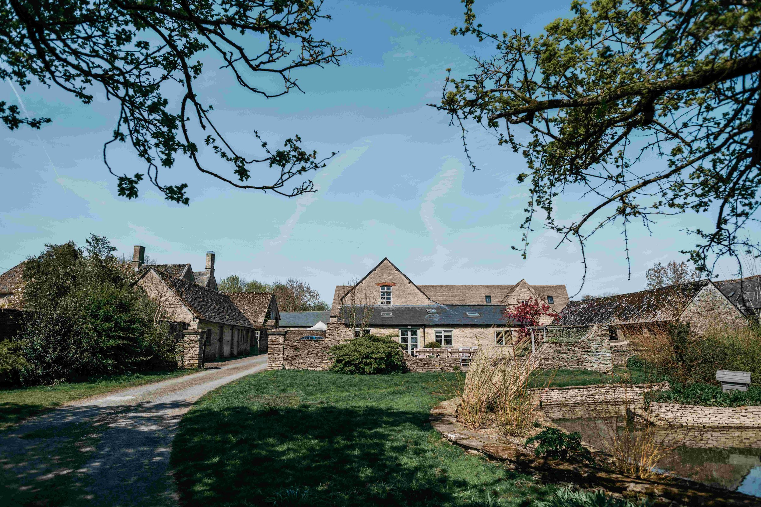 A quiet village scene with stone cottages, trees, and a grassy area under a clear blue sky.