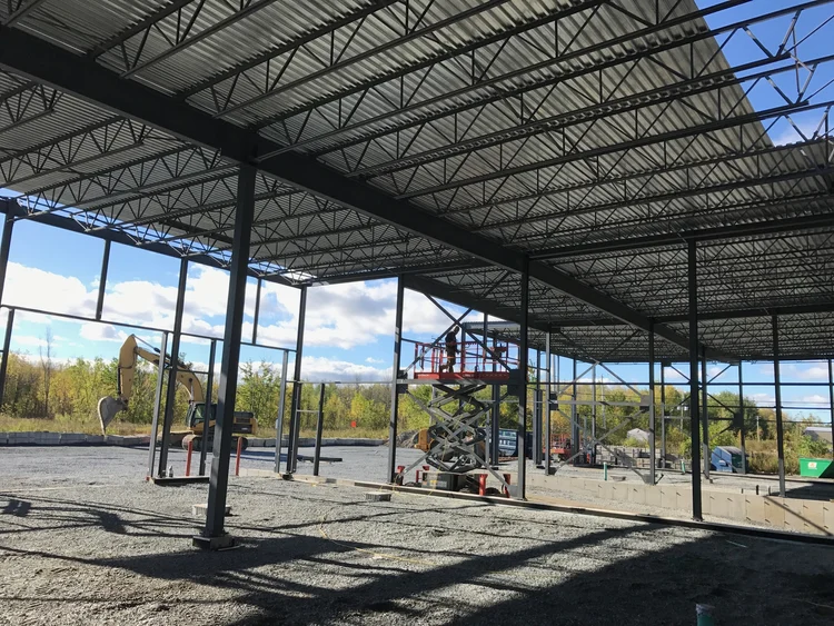 Construction d'une nouvelle structure avec des équipements de levage et des excavatrices dans un espace ouvert.