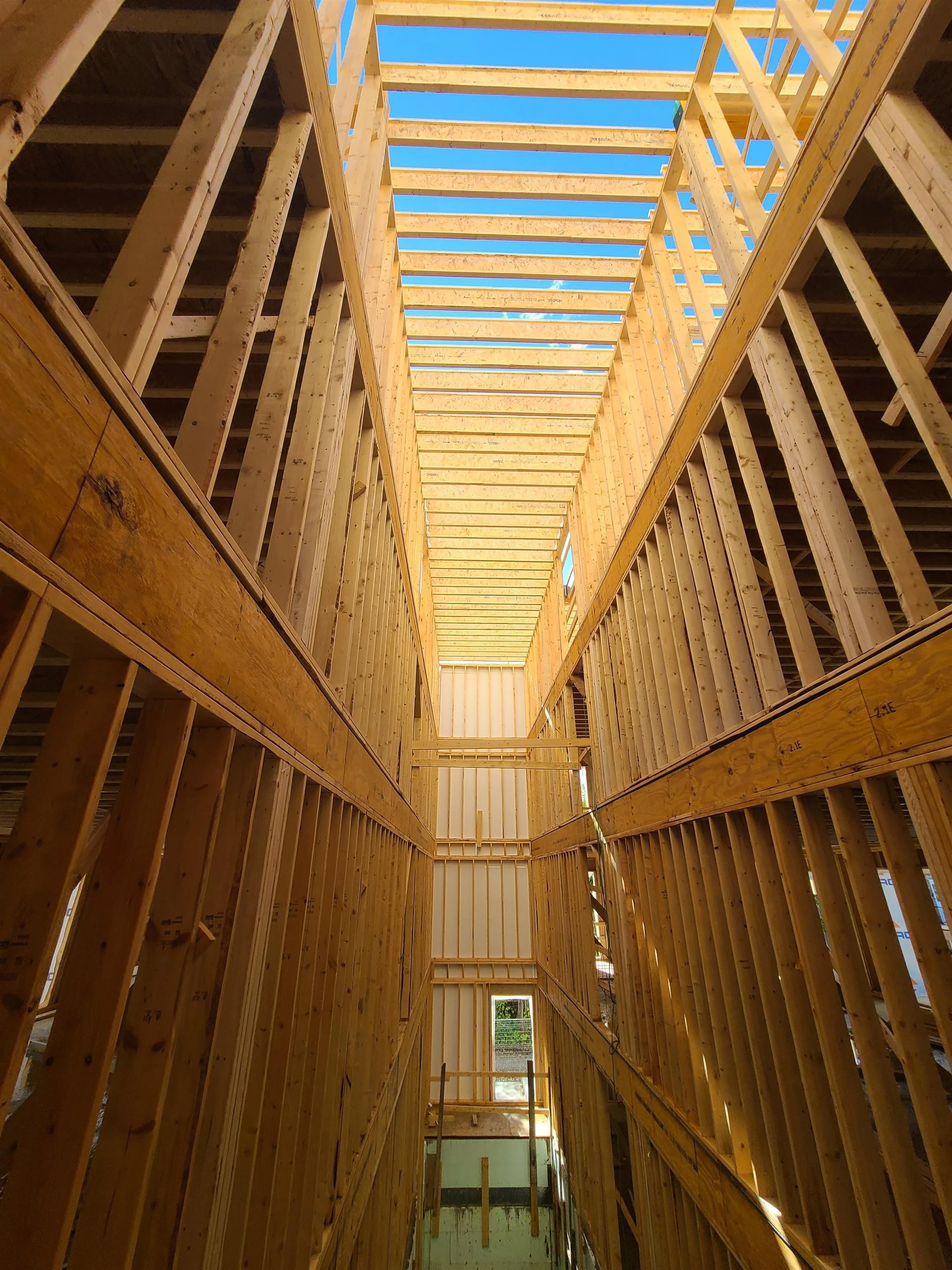 Structure en bois en construction avec cadres en bois et ouverture dans le plafond, vue vers le haut lors de la construction.